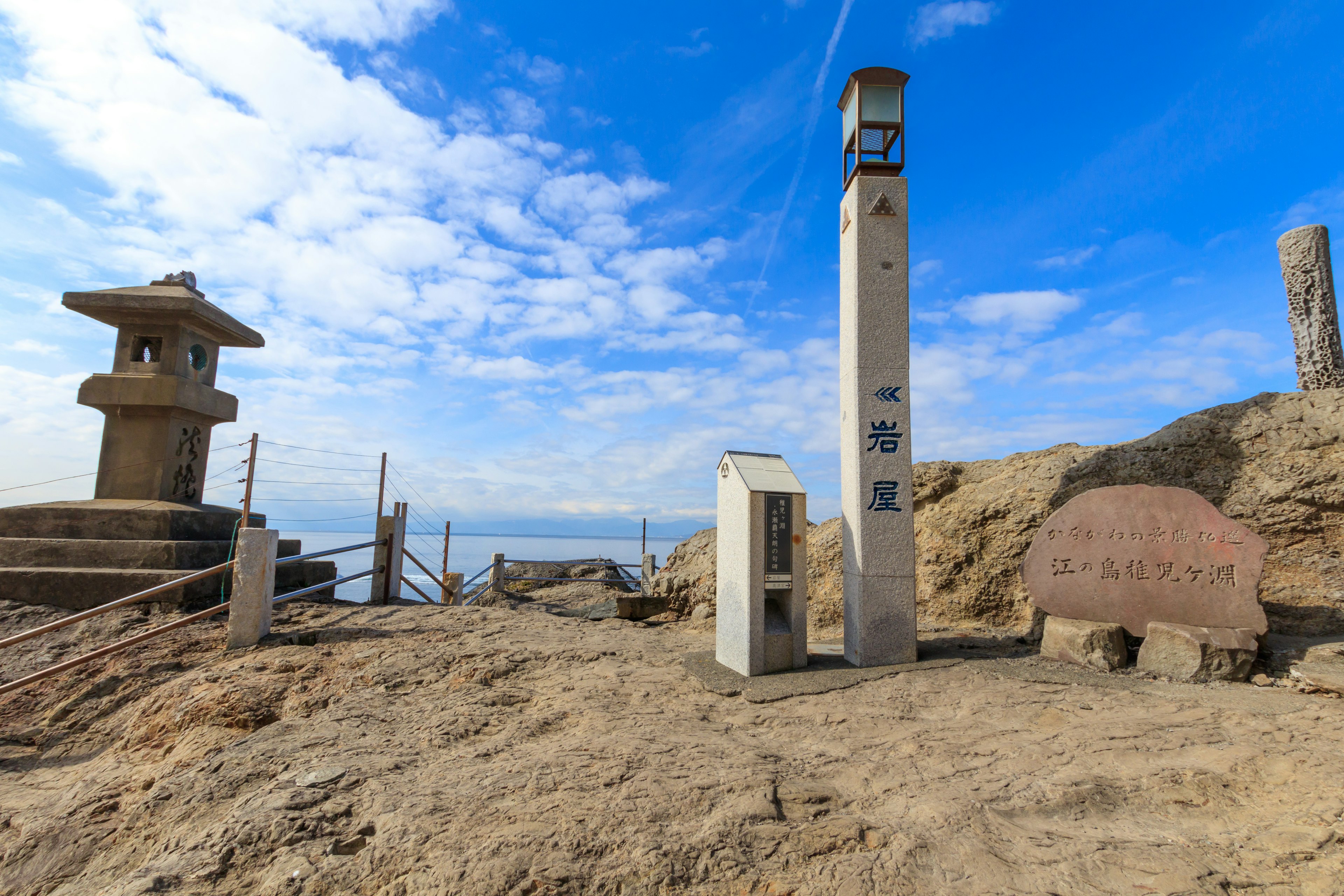 Vista escénica con una linterna de piedra y monumentos en una costa rocosa