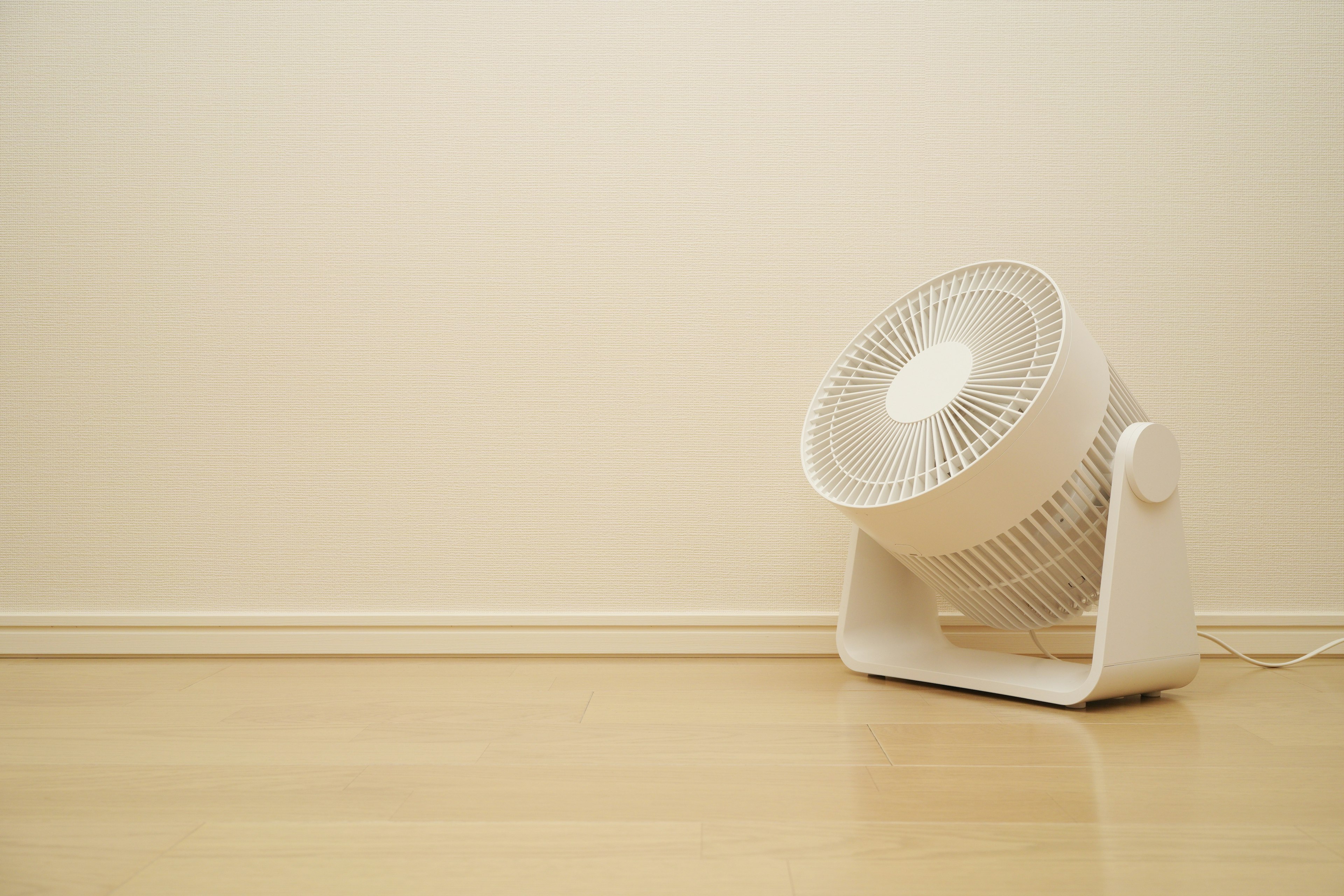 Un ventilatore bianco posizionato sul pavimento in un ambiente interno minimalista