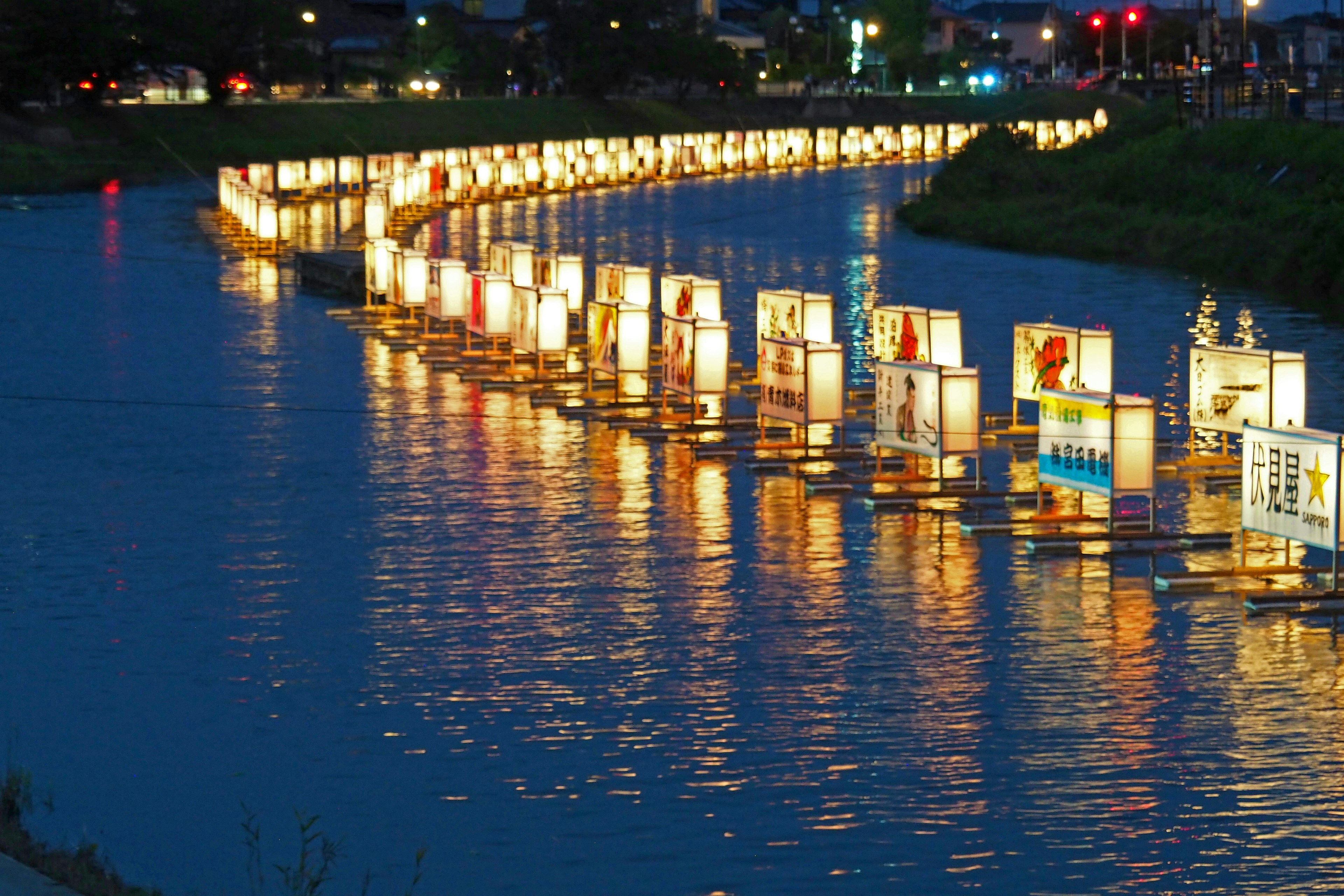 夜の川に浮かぶ灯篭の列とその反射