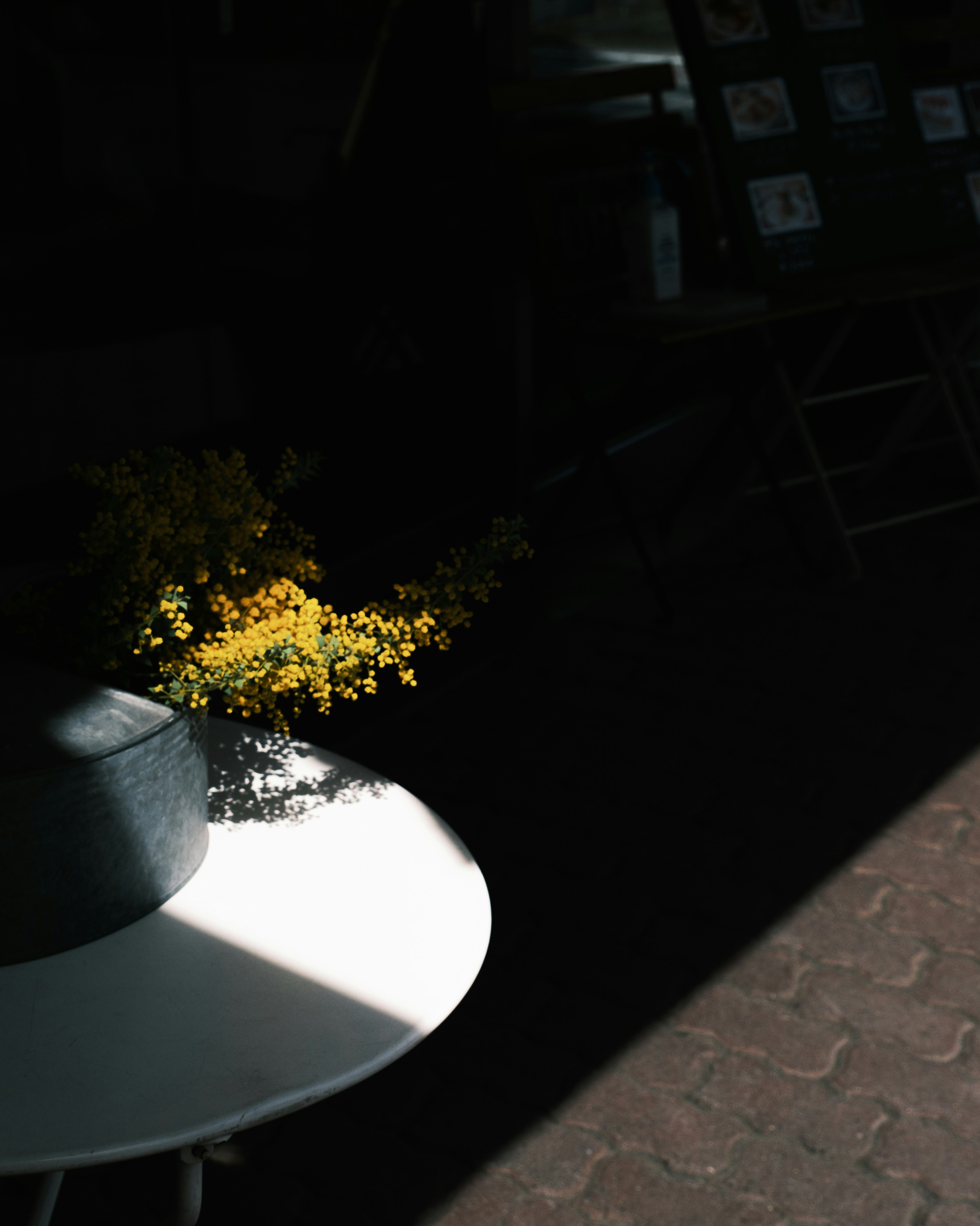 A white vase on a table with yellow flowers arranged inside