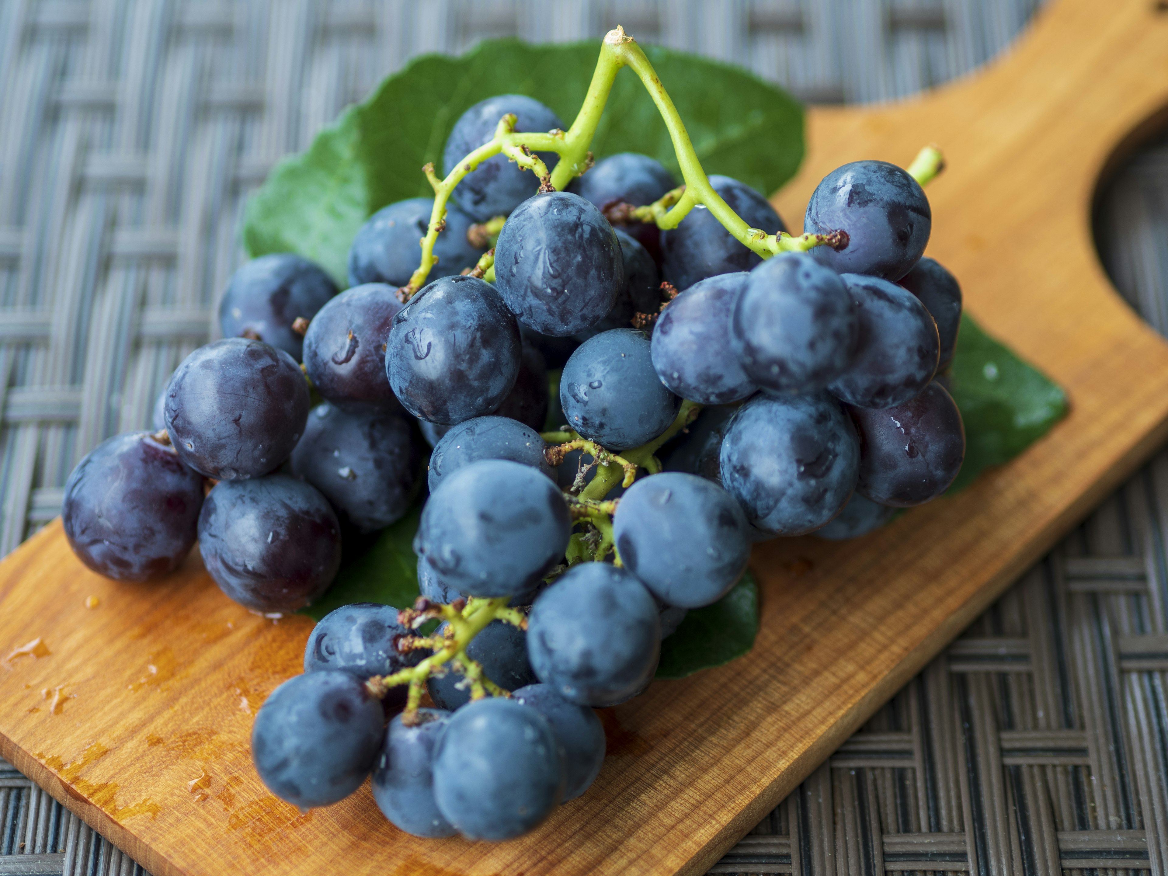 Uva blu-viola fresca su un tagliere di legno