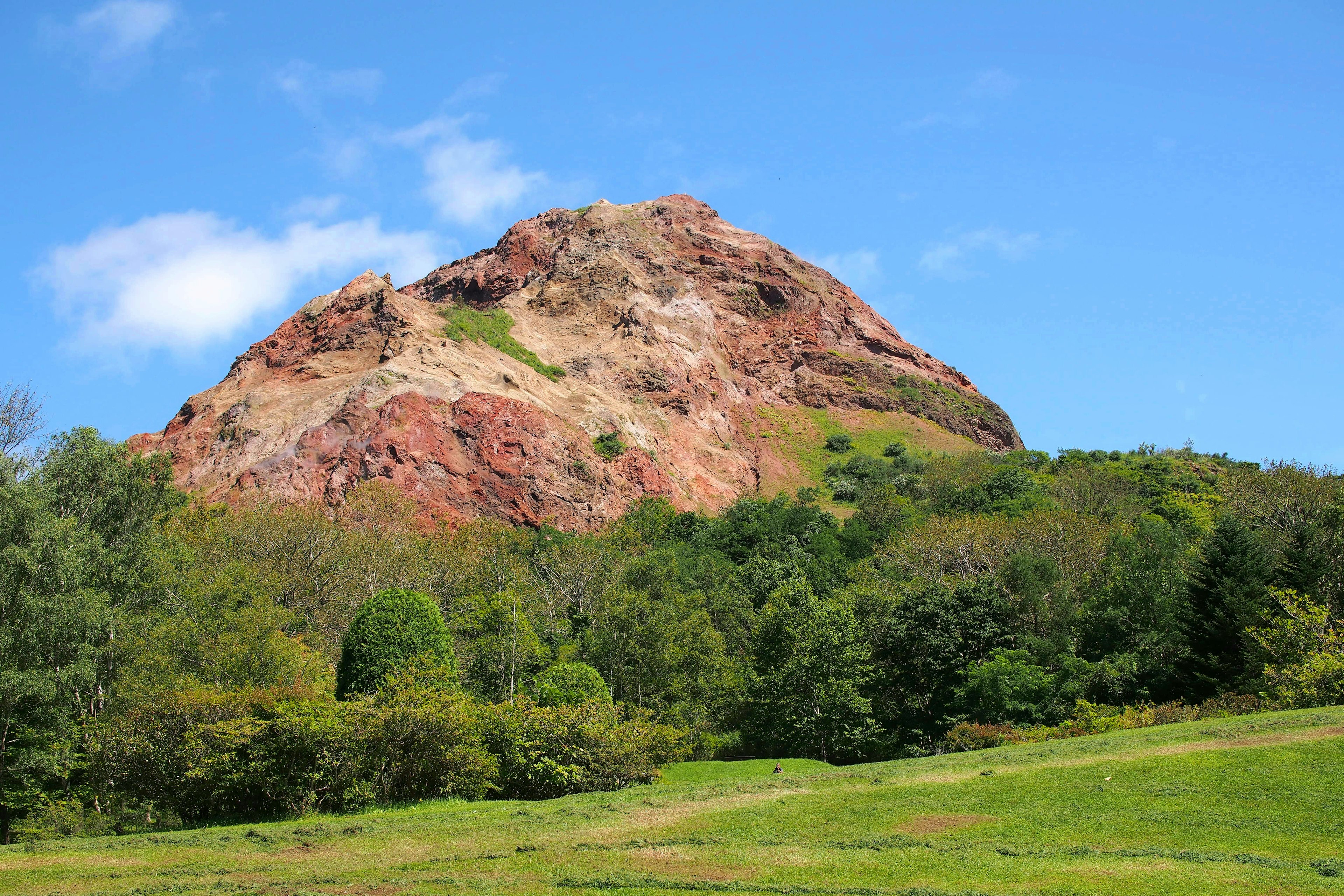 Gunung dengan formasi batu berwarna dan langit biru