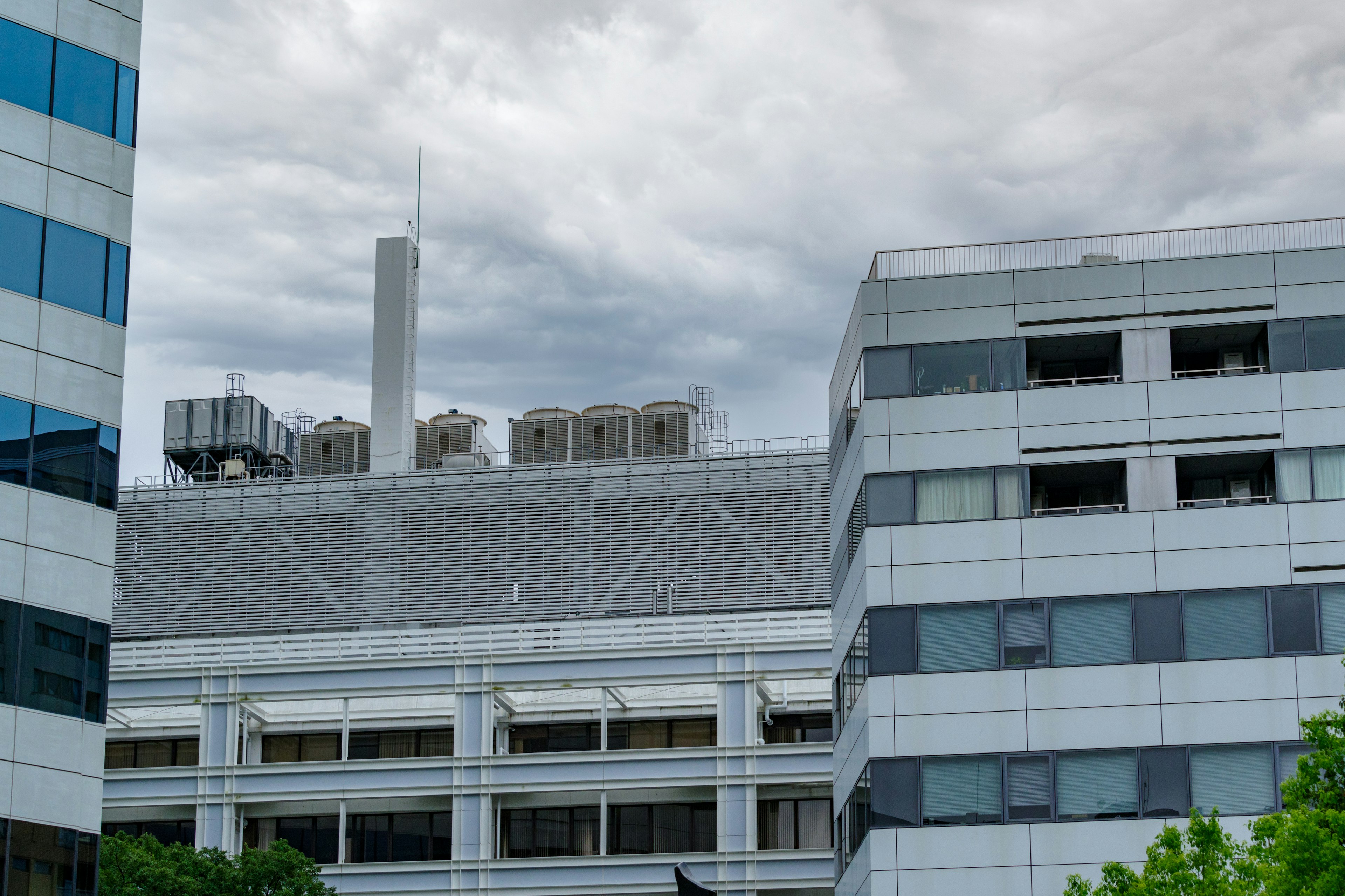 都市のビルの屋上に設置された空調機器と煙突を持つ建物の風景