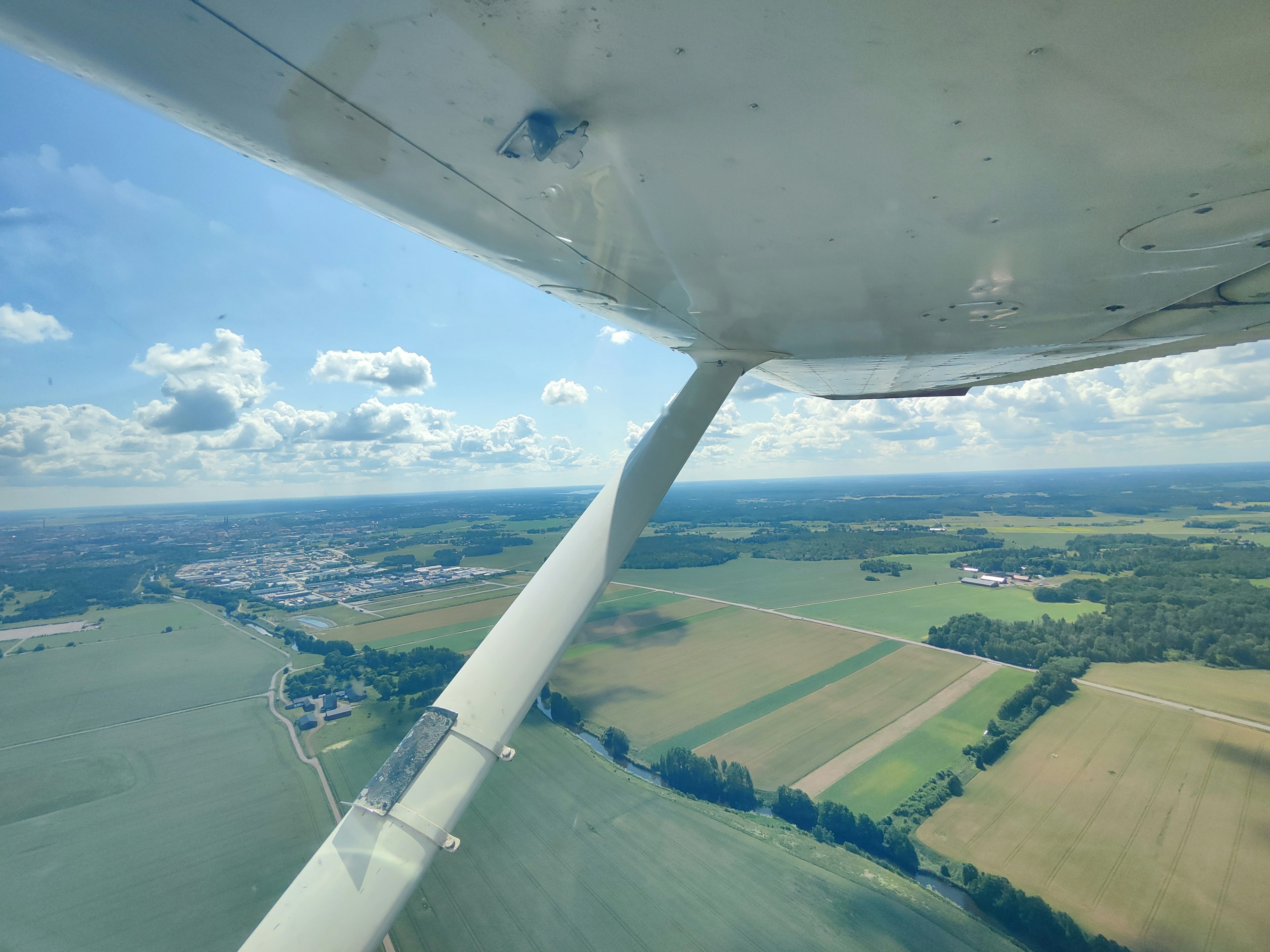 Luftaufnahme von grünen landwirtschaftlichen Flächen mit dem Flügel eines Flugzeugs