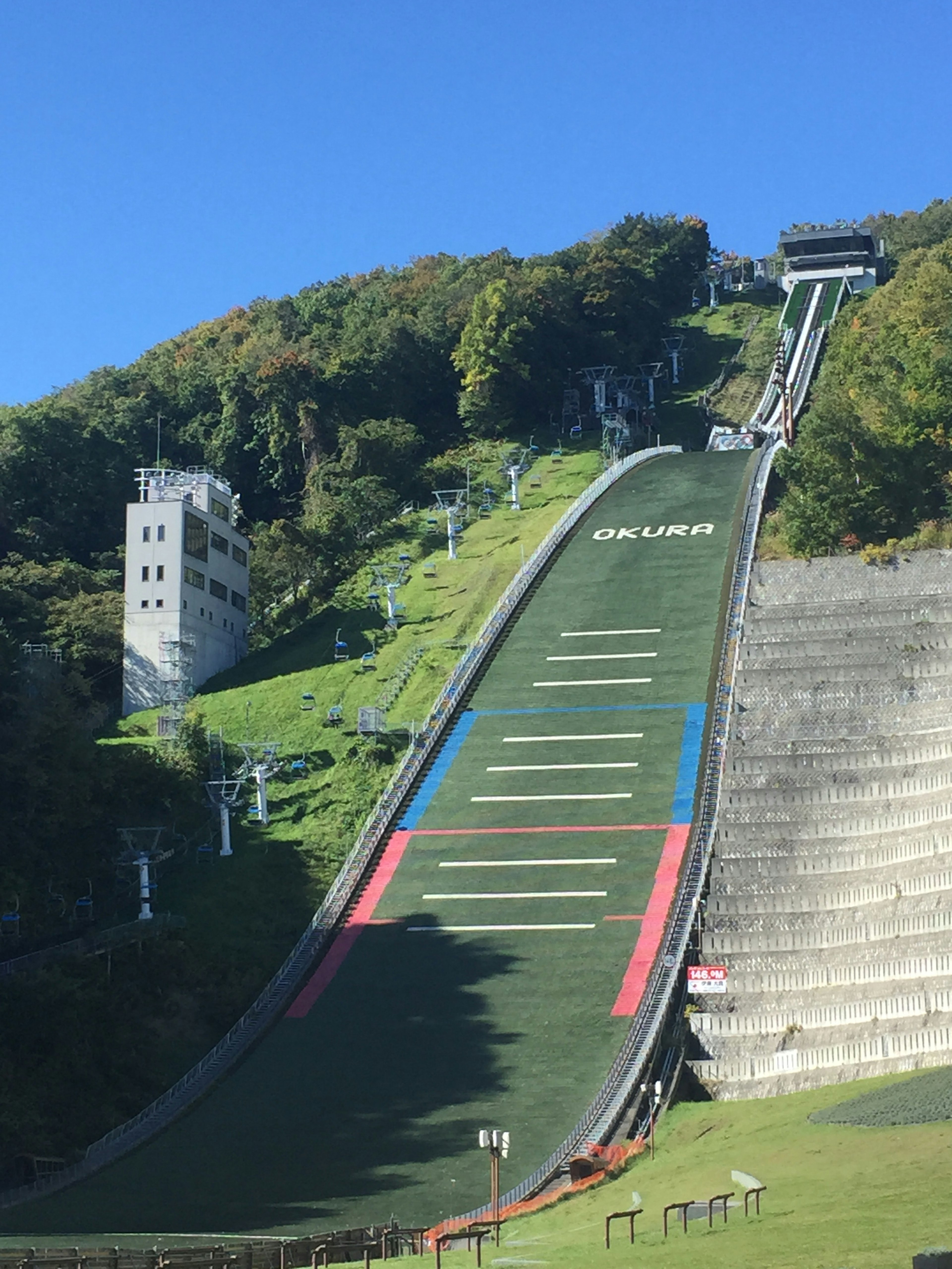 スキージャンプ台の緑の滑走路と青い空の風景