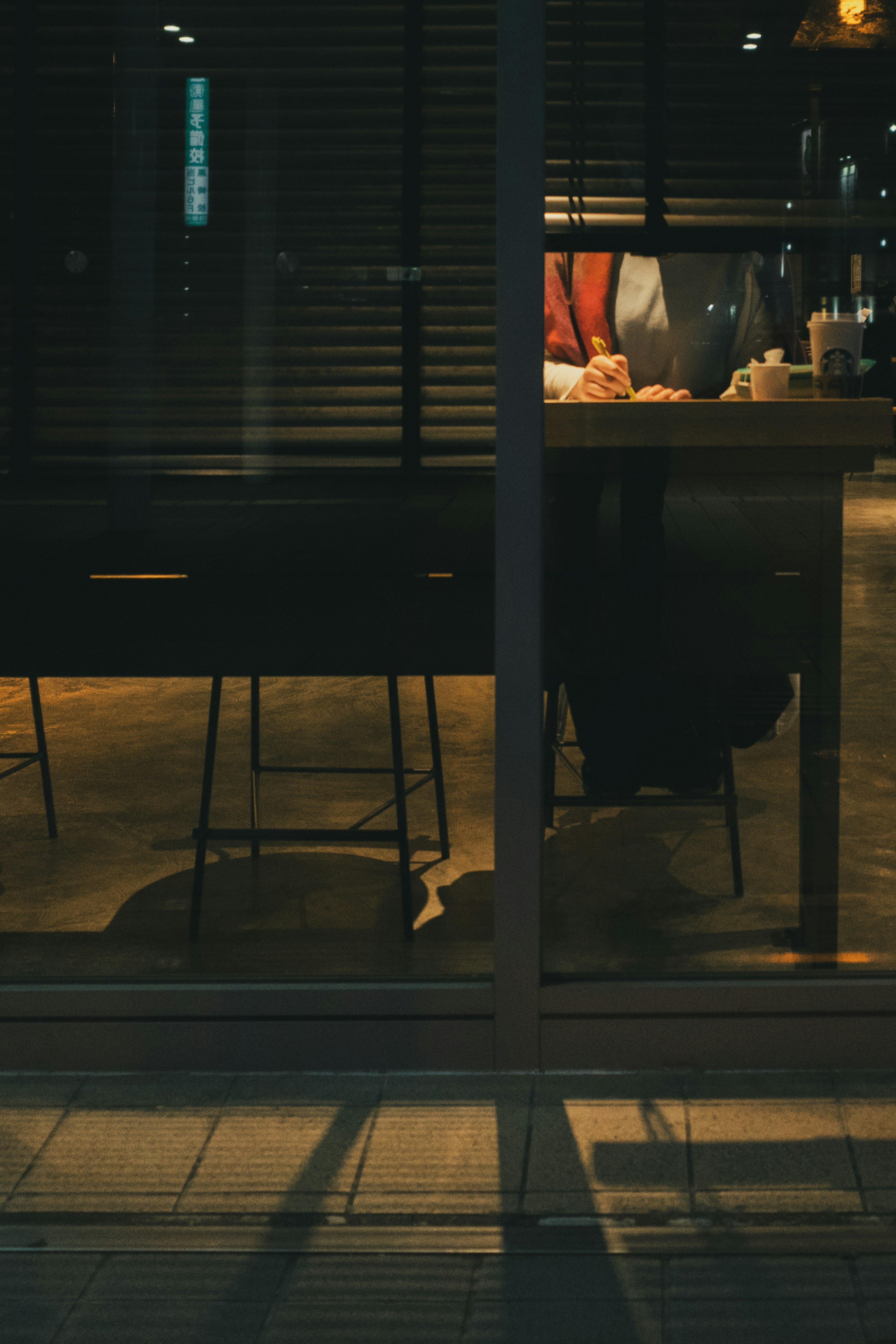 Vue à travers la fenêtre d'un café faiblement éclairé avec des ombres de table et de chaise