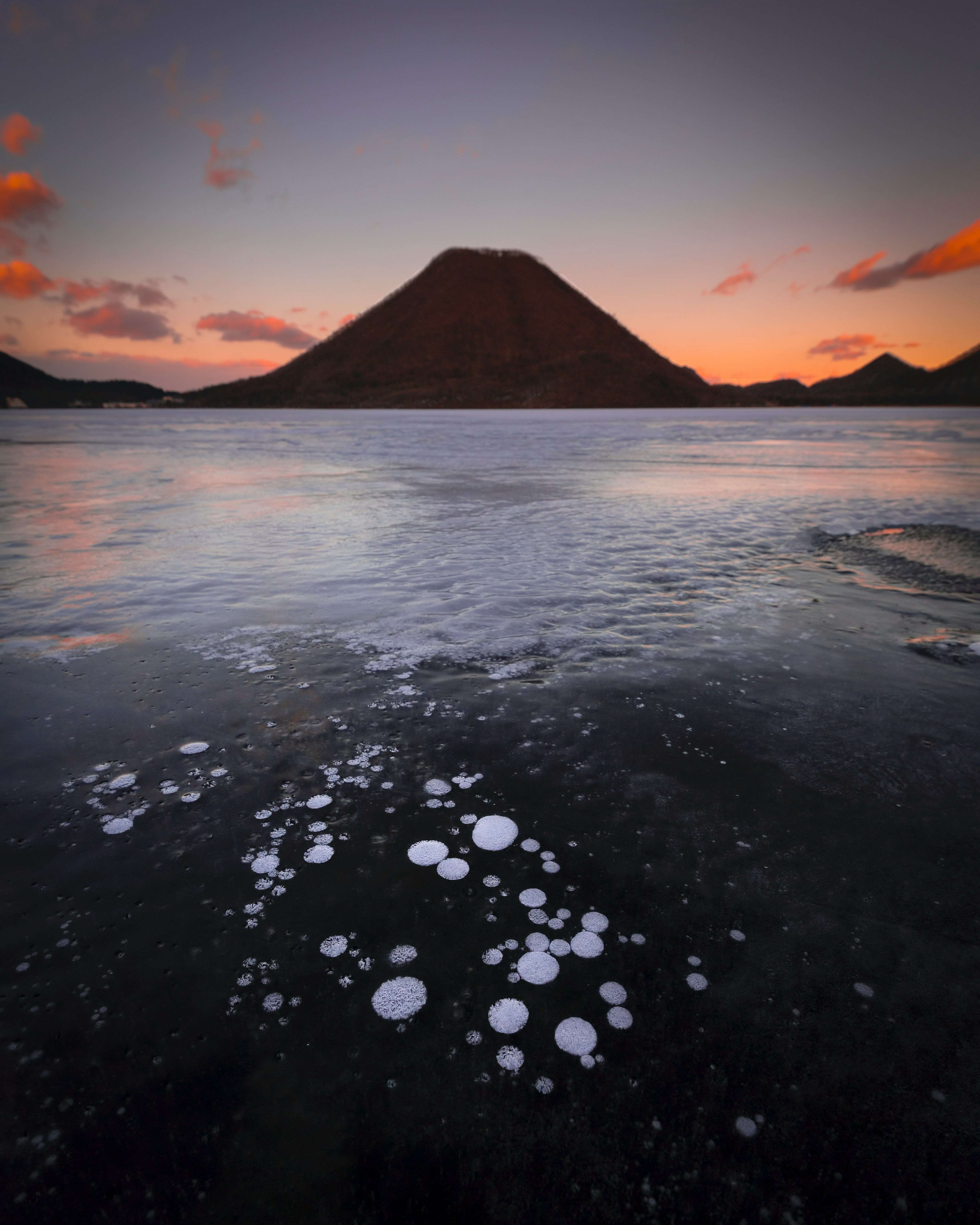 湖と山の美しい風景 静かな水面に泡が浮かぶ夕暮れ