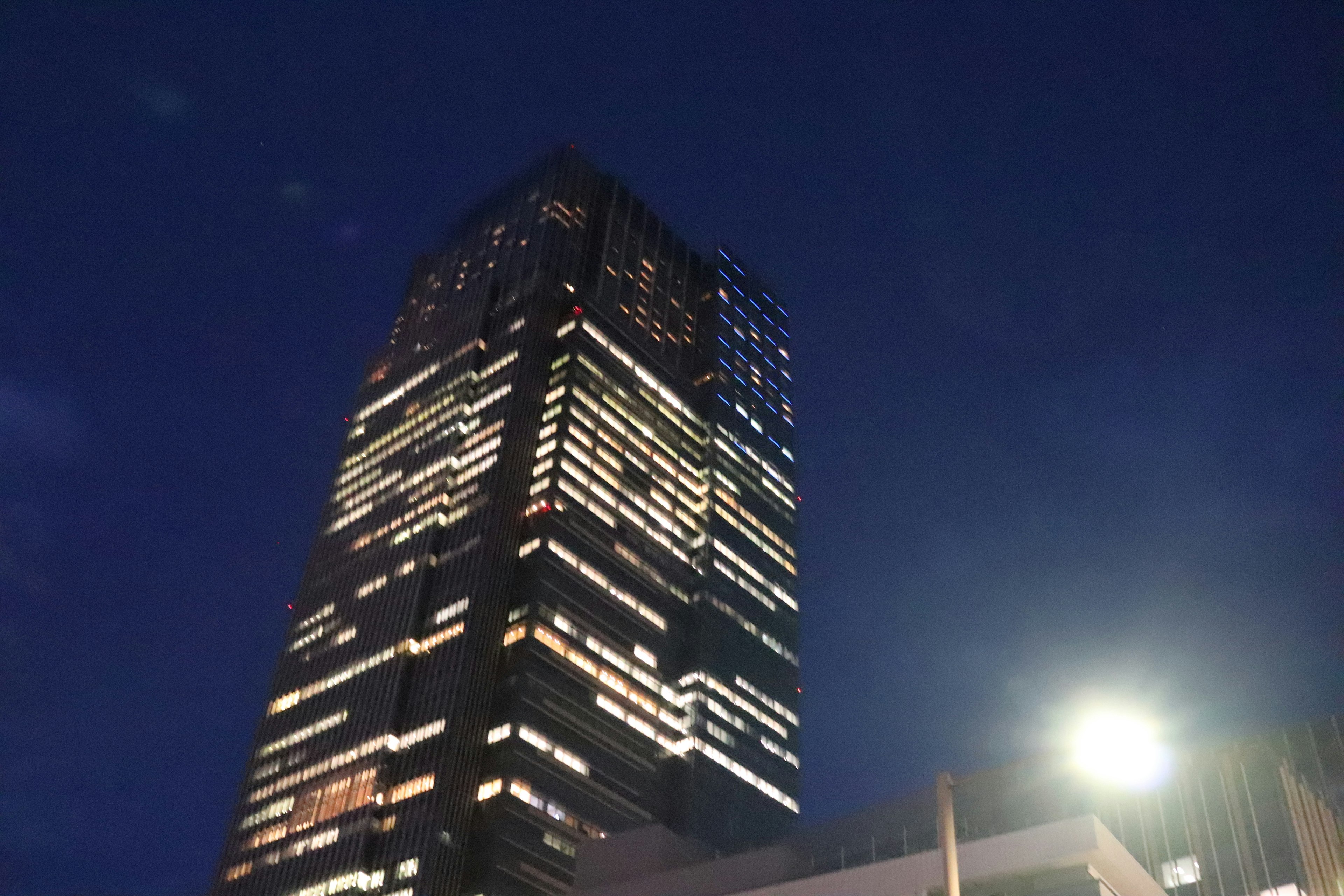 Gedung pencakar langit yang diterangi di malam hari dengan jendela yang bersinar