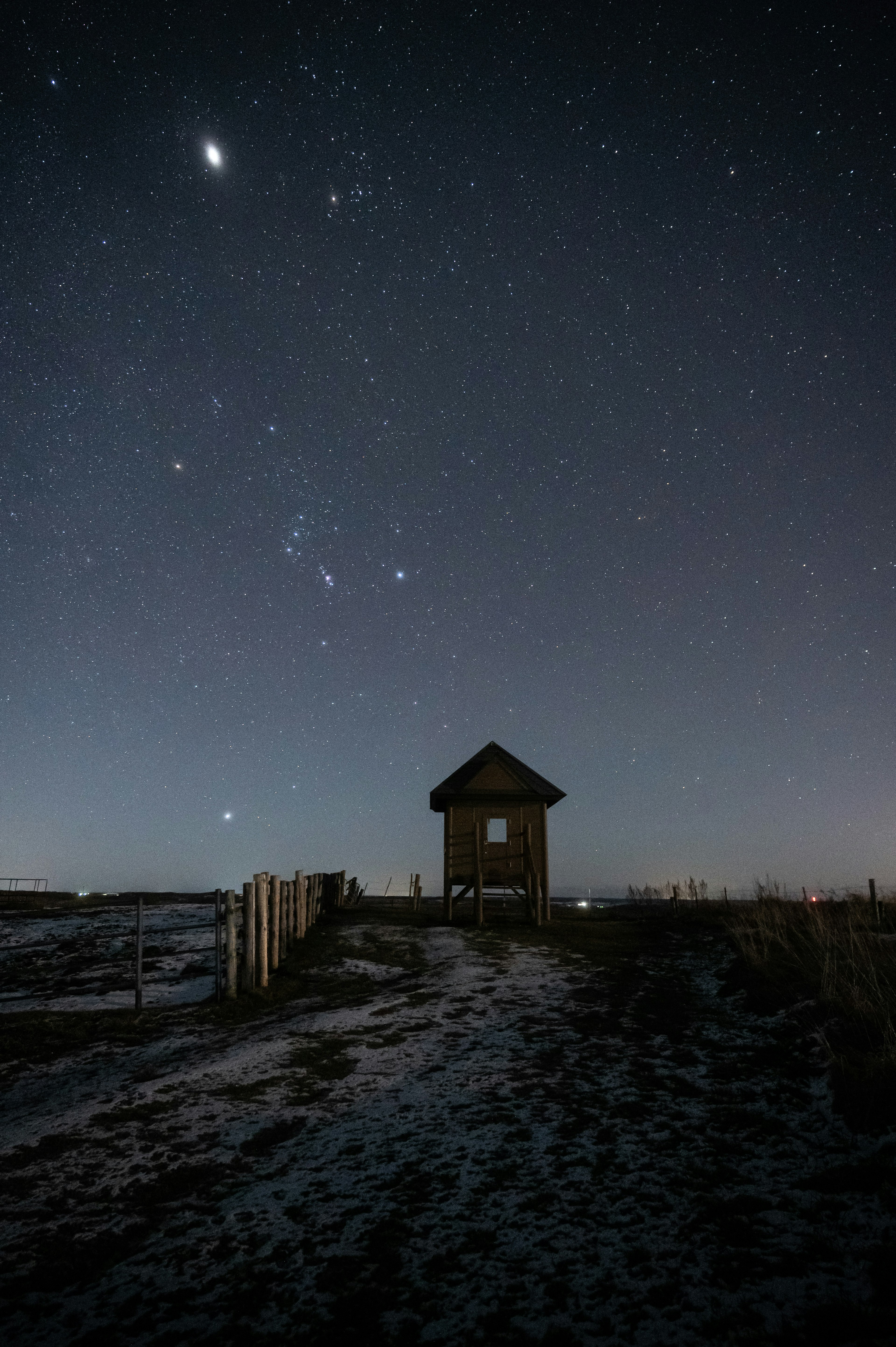 夜空に星が輝く中、孤立した小屋が見える風景