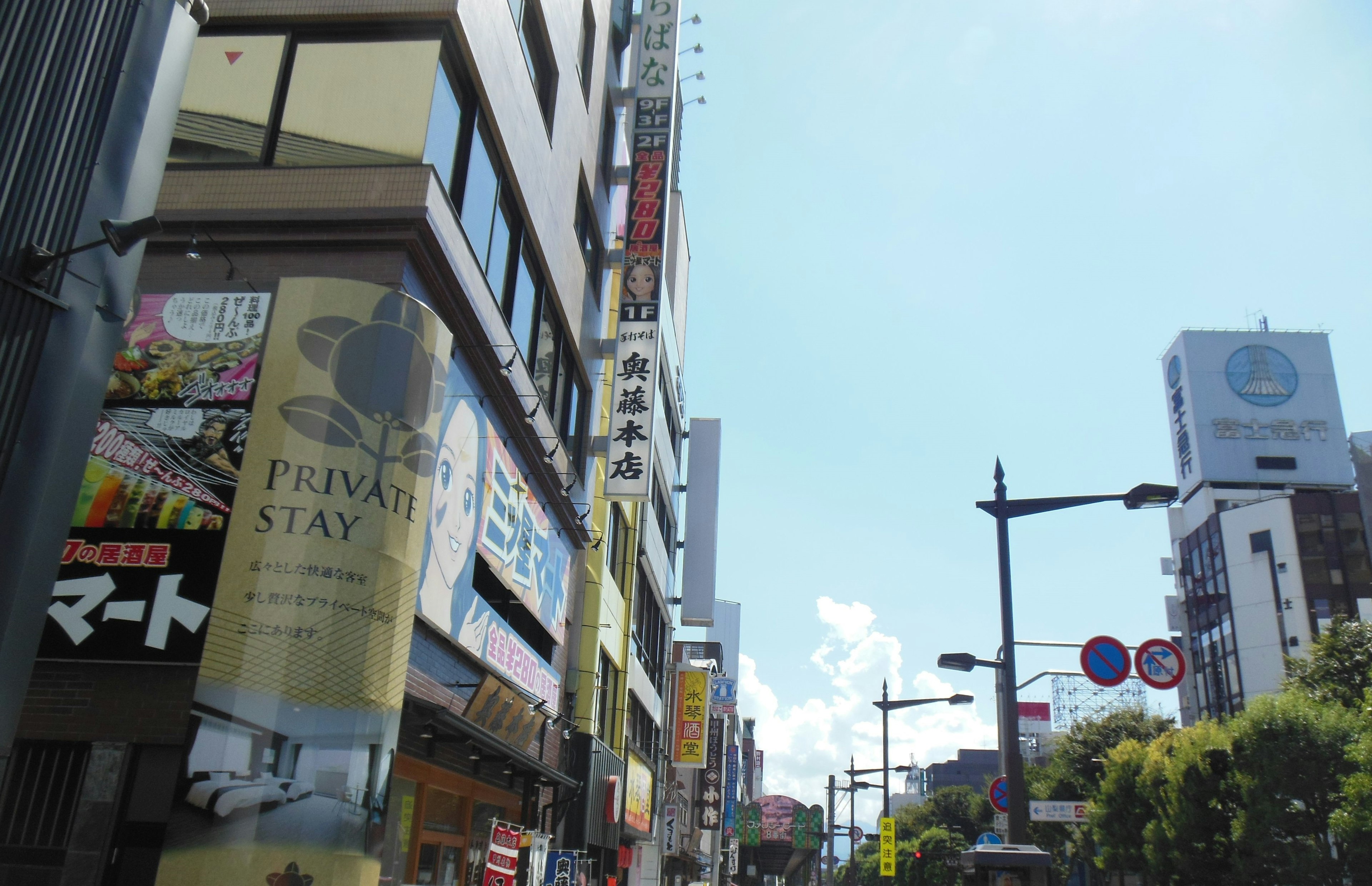 Street view with building signs blue sky and clouds visible