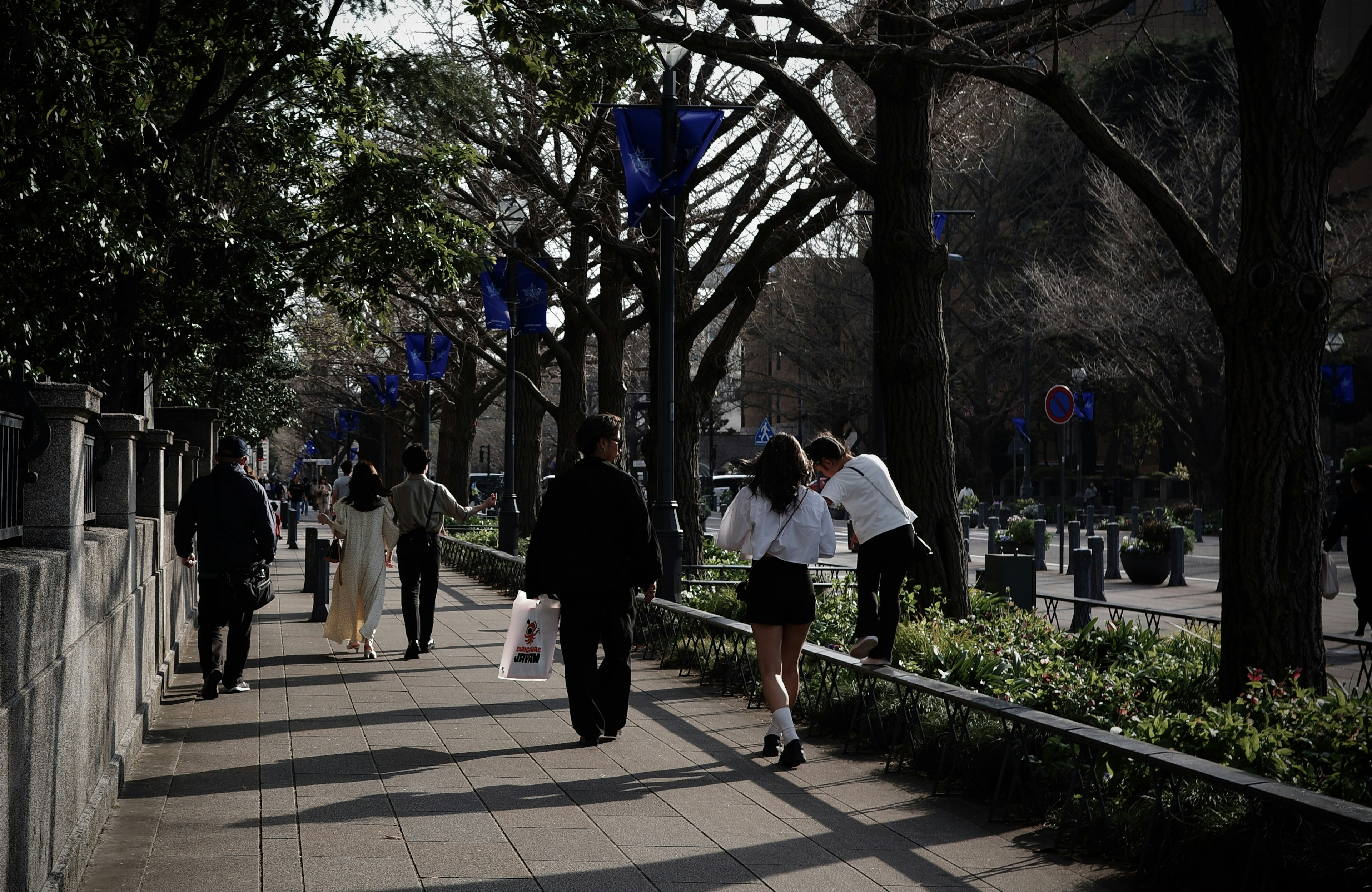 Escena urbana con personas caminando árboles y decoraciones azules