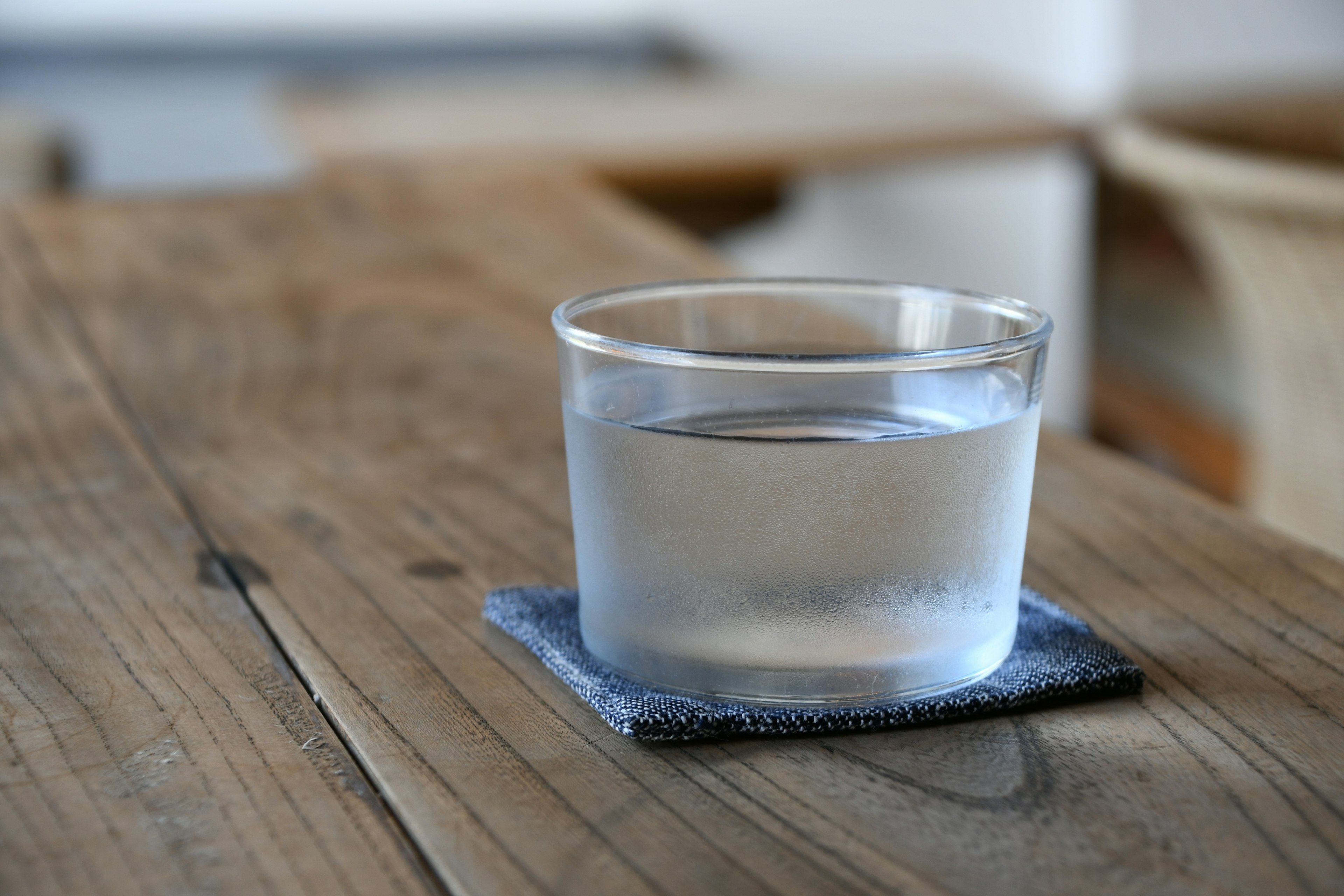 A clear glass of water placed on a wooden table