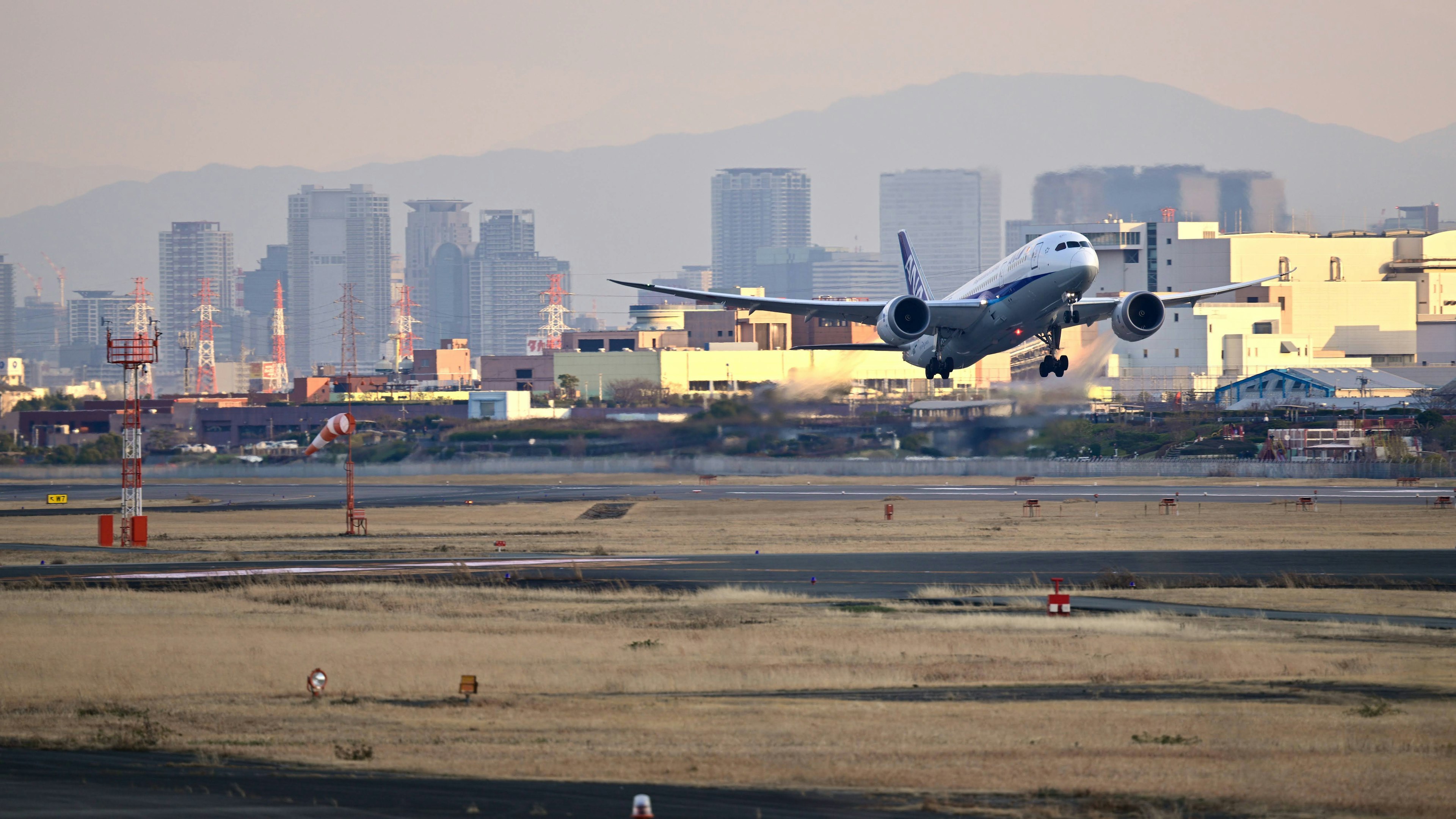 Flugzeug, das an einem Flughafen mit einer Stadtsilhouette im Hintergrund abhebt