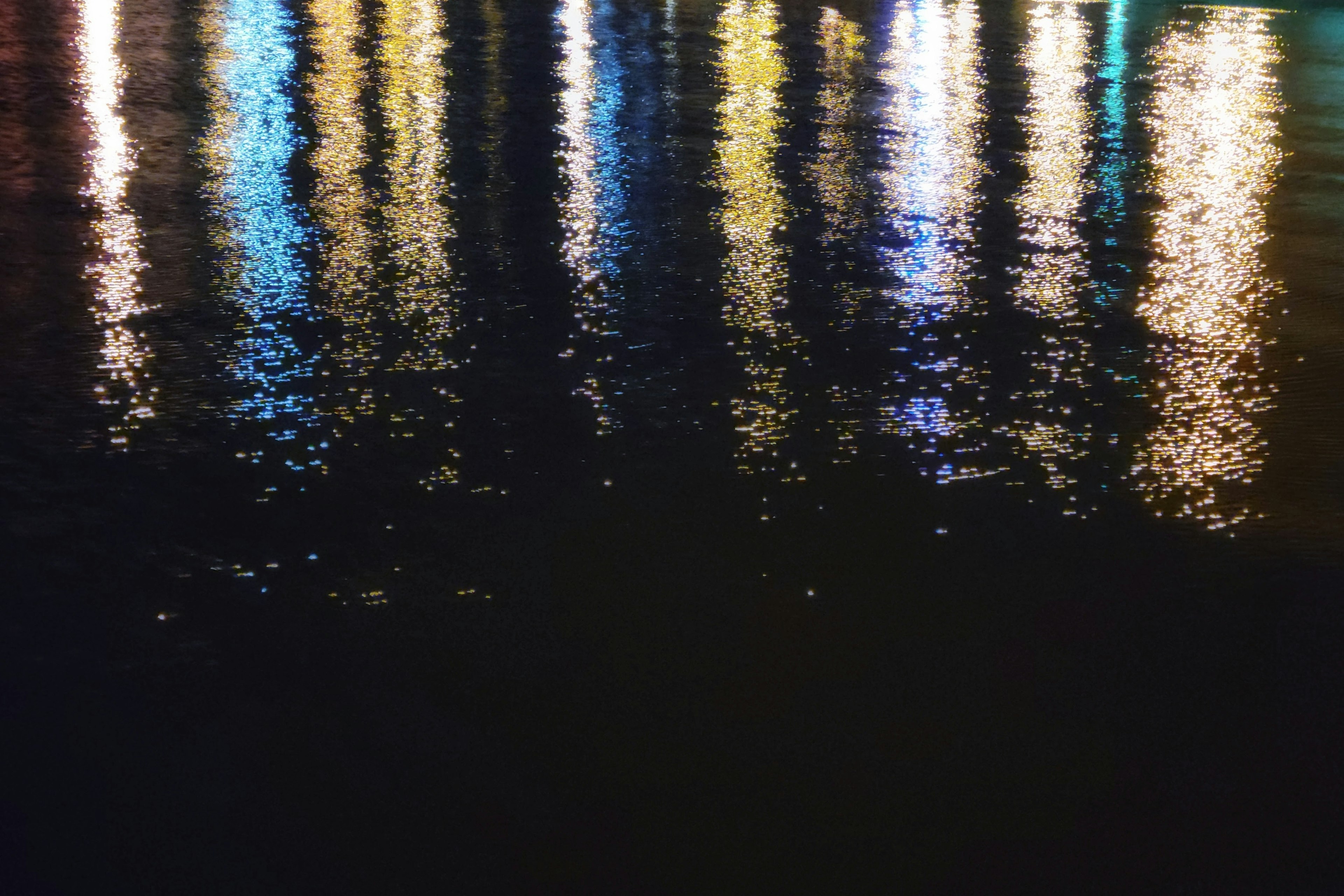 Colorful reflections of lights on the water surface dark background