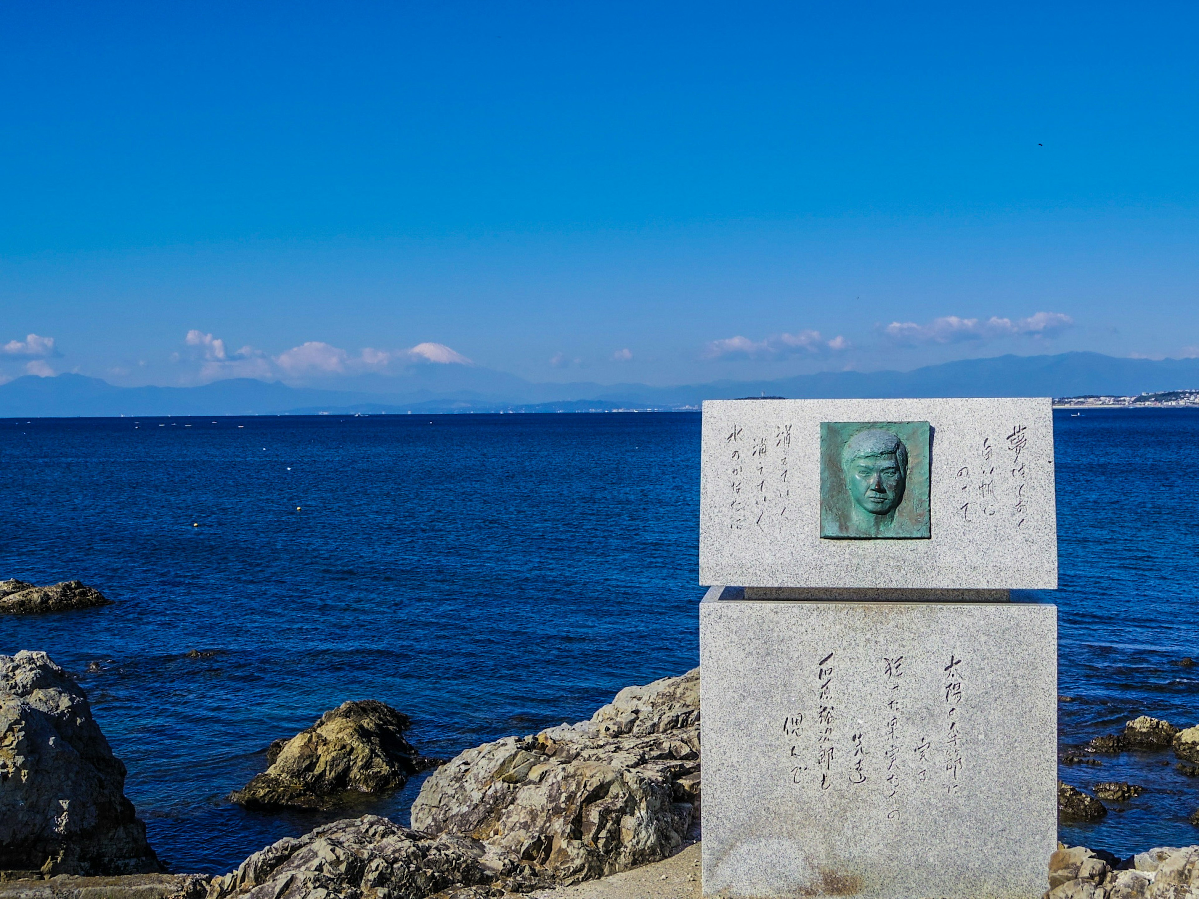 Küstenmonument mit Bronzetafel und blauem Meer