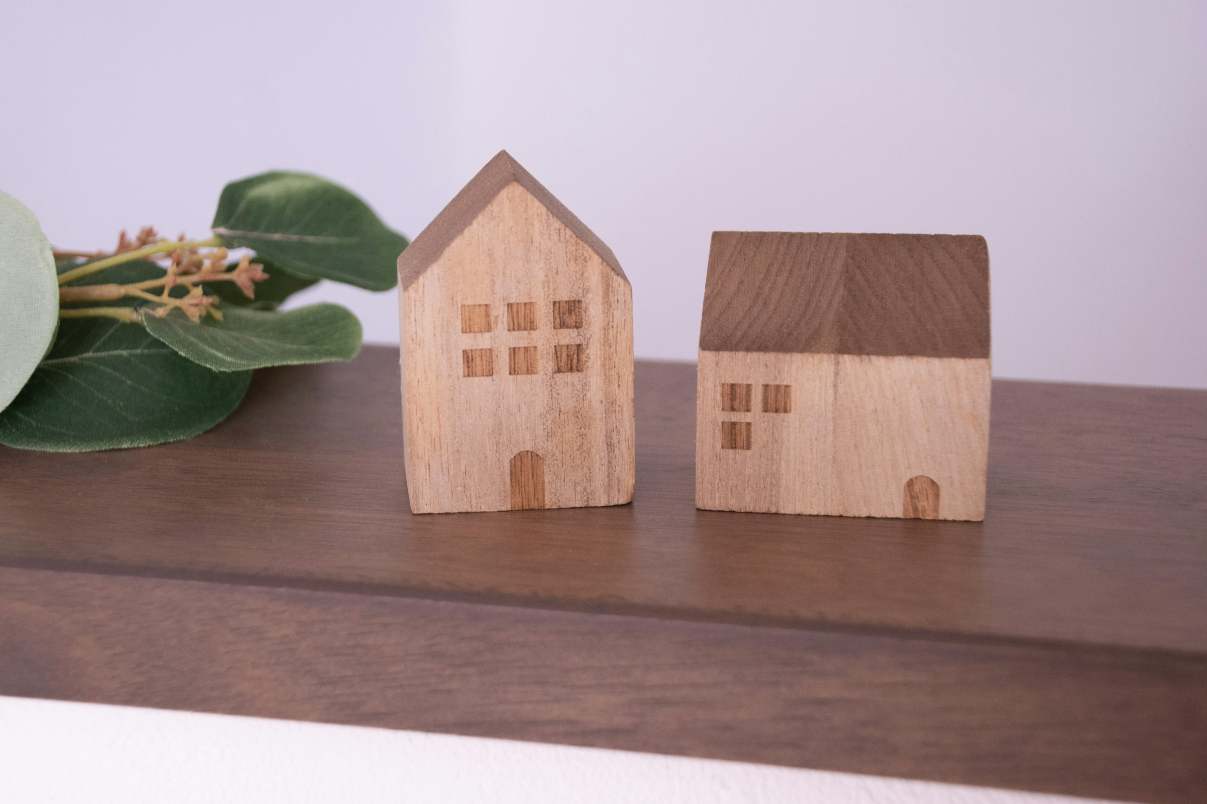 Dos modelos de casas de madera exhibidos uno al lado del otro uno es una casa de dos pisos y el otro es una casa de un piso