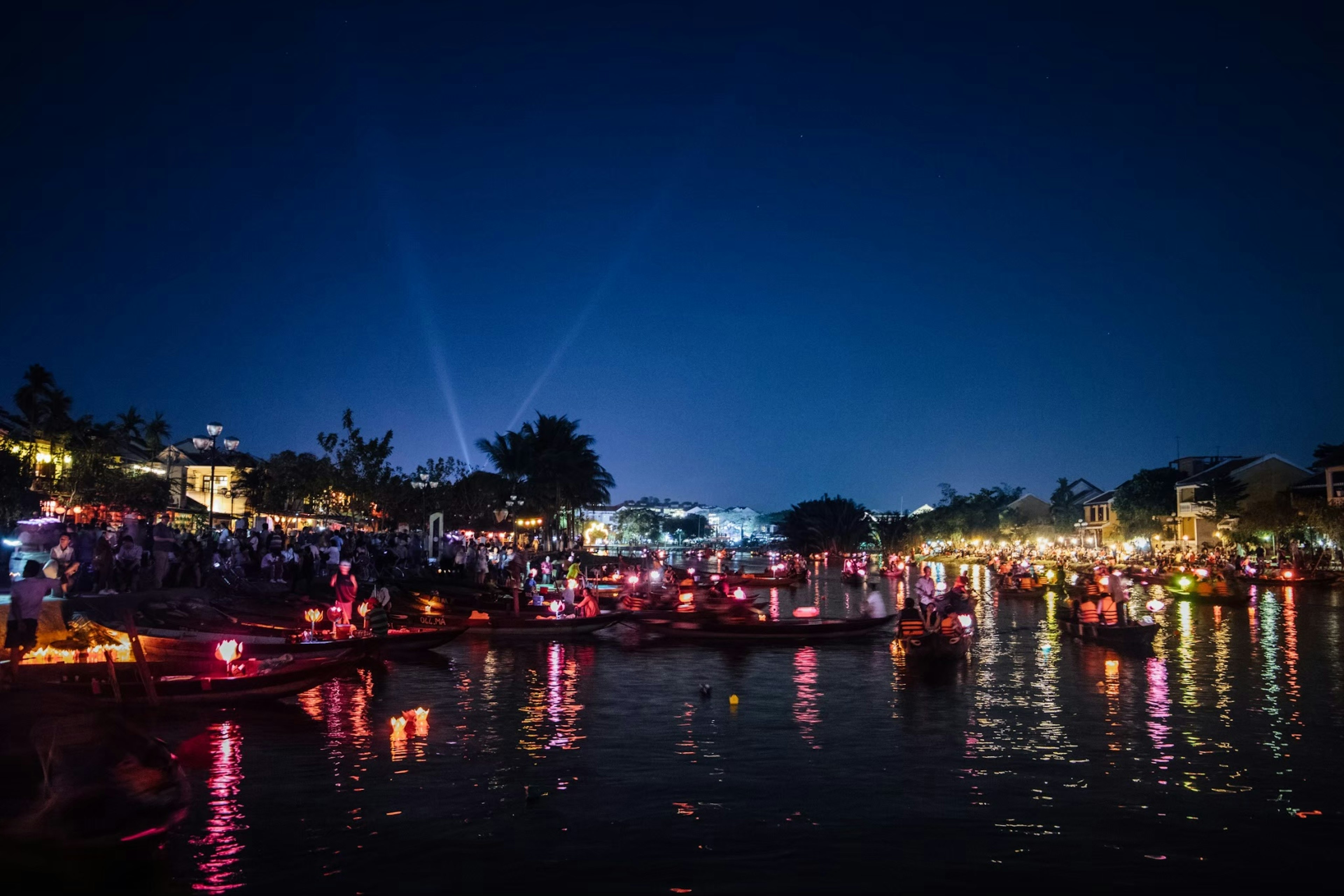 Decorated boats floating on a river at night with bright lights