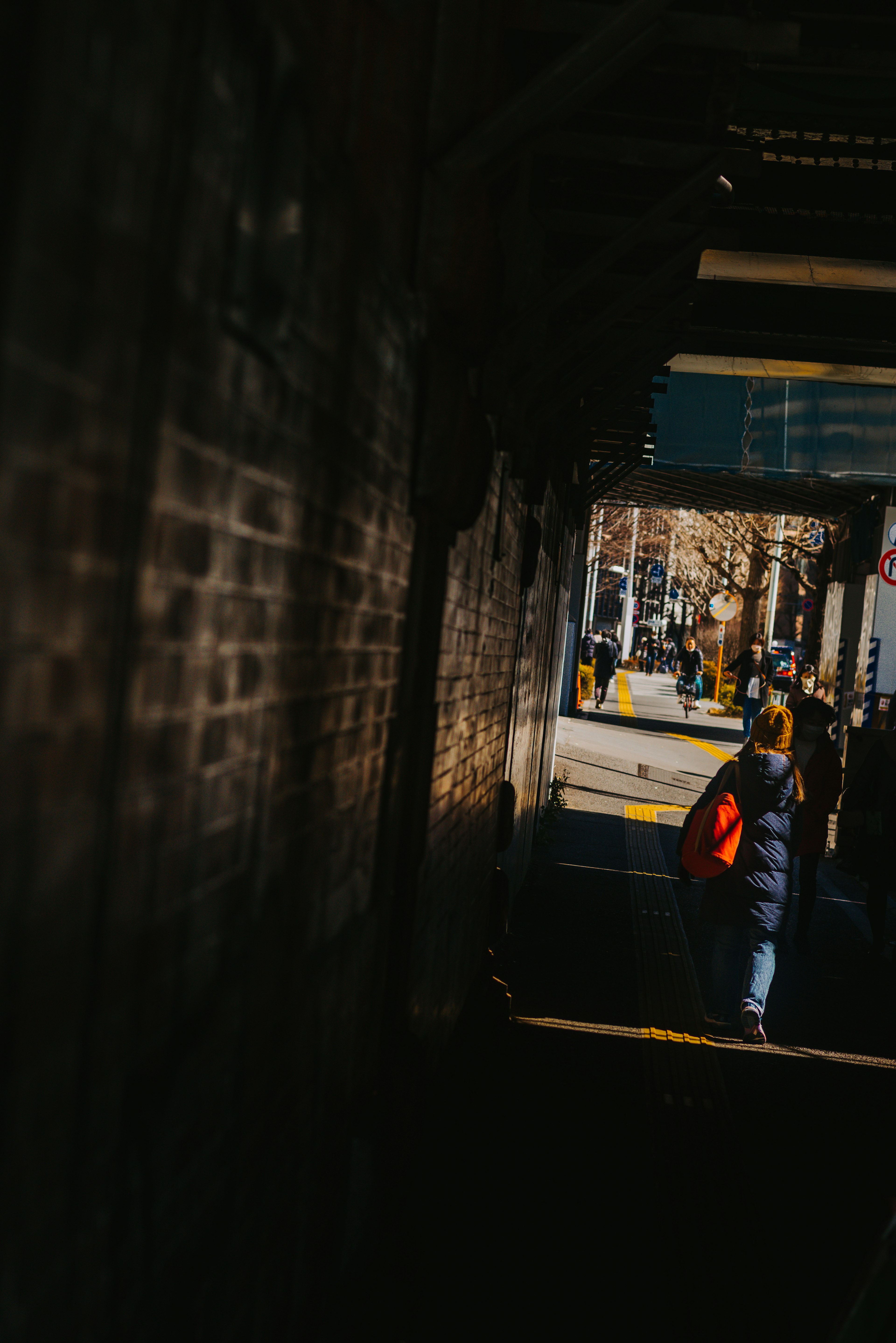 Silhouetted figure walking in sunlight through a narrow passageway