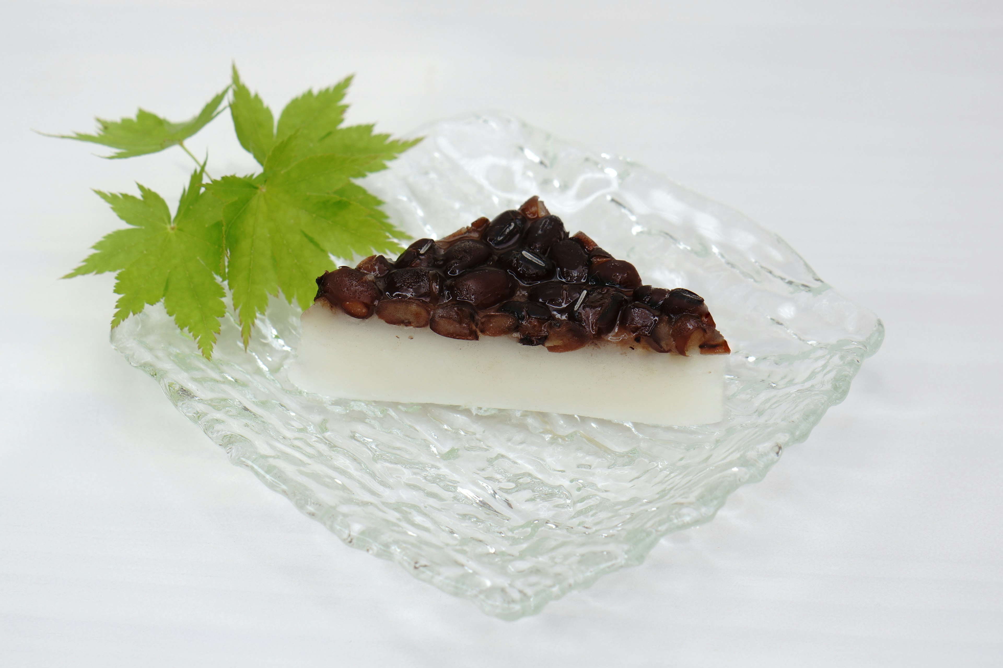 Dessert featuring white confection topped with black bean paste and green leaves