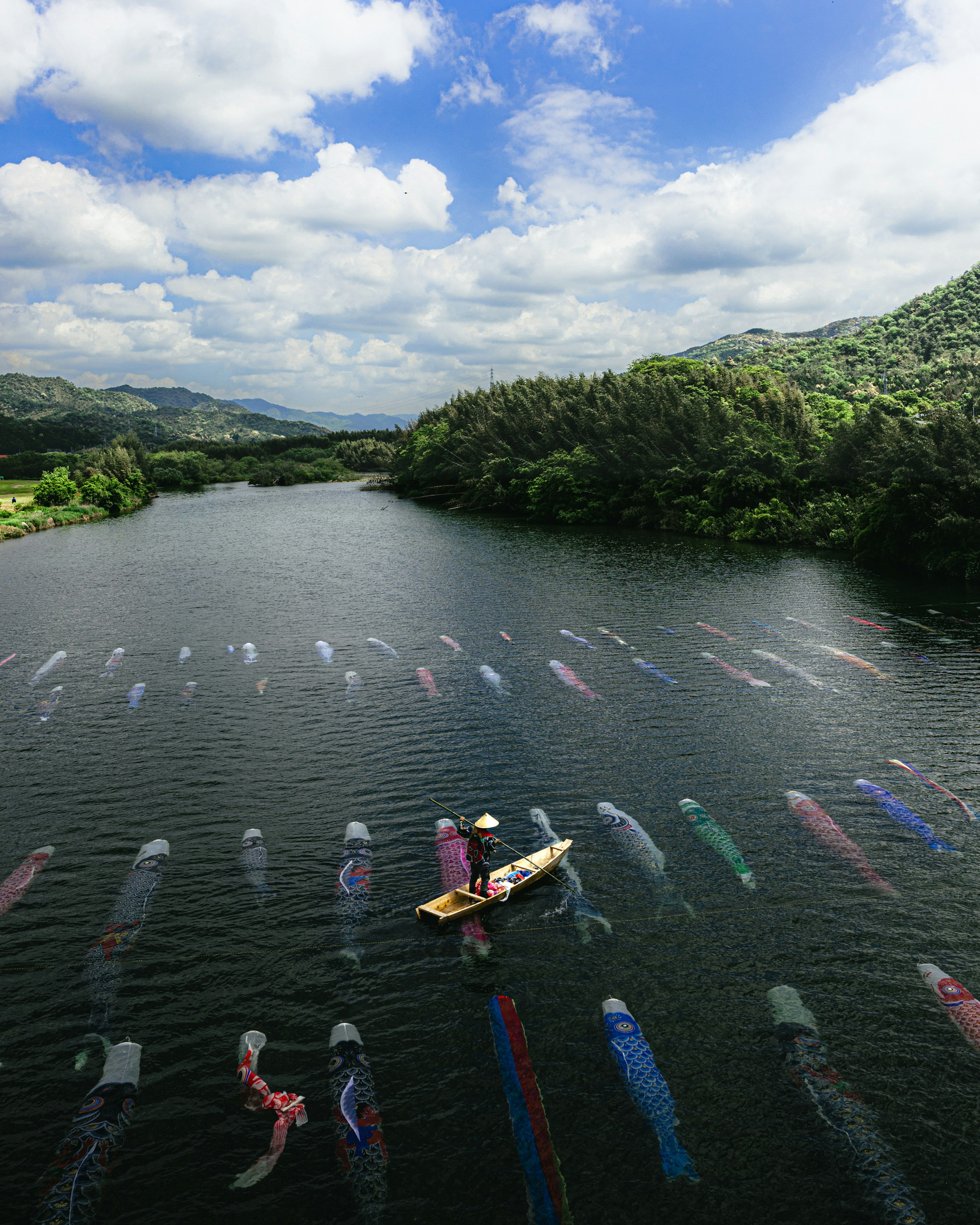 A person paddling a boat surrounded by colorful koi flags in a river