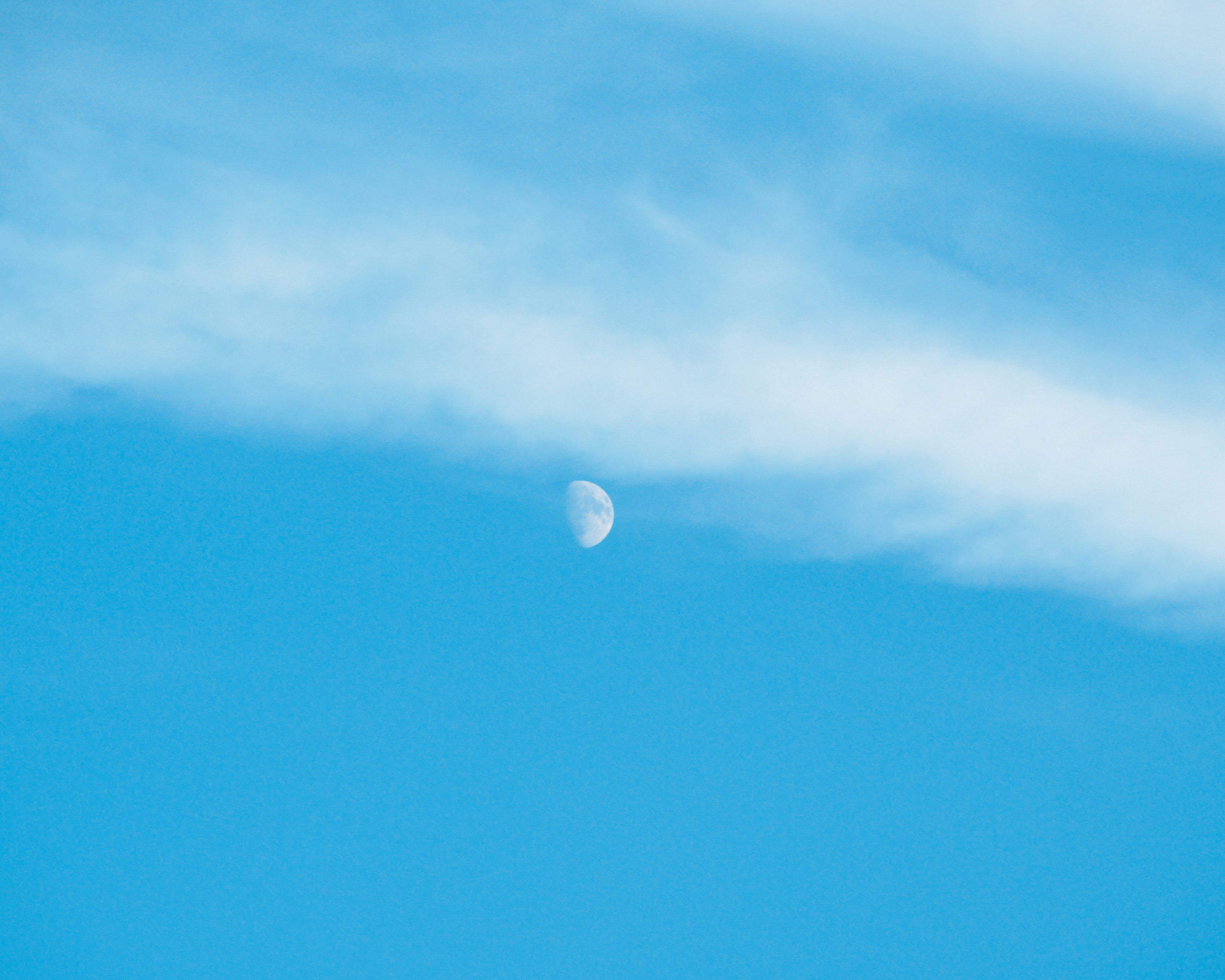 Lune croissante flottant dans un ciel bleu avec des nuages fins