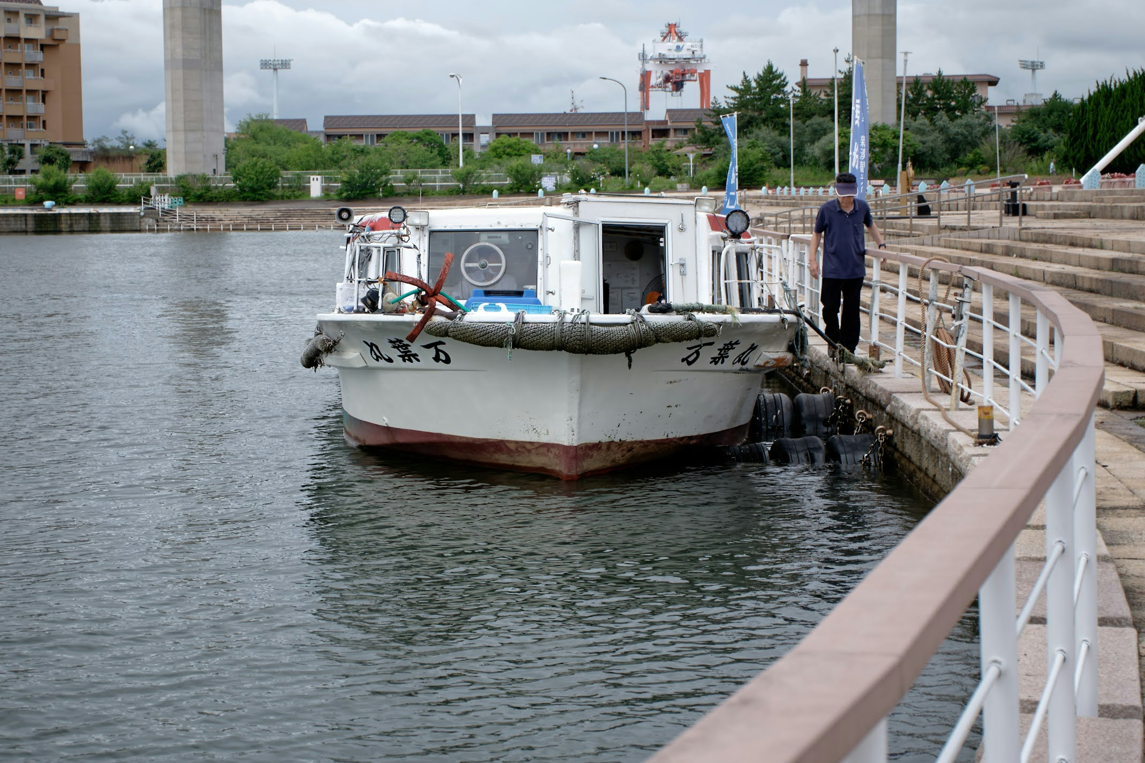 A small boat docked at the waterfront with a person nearby