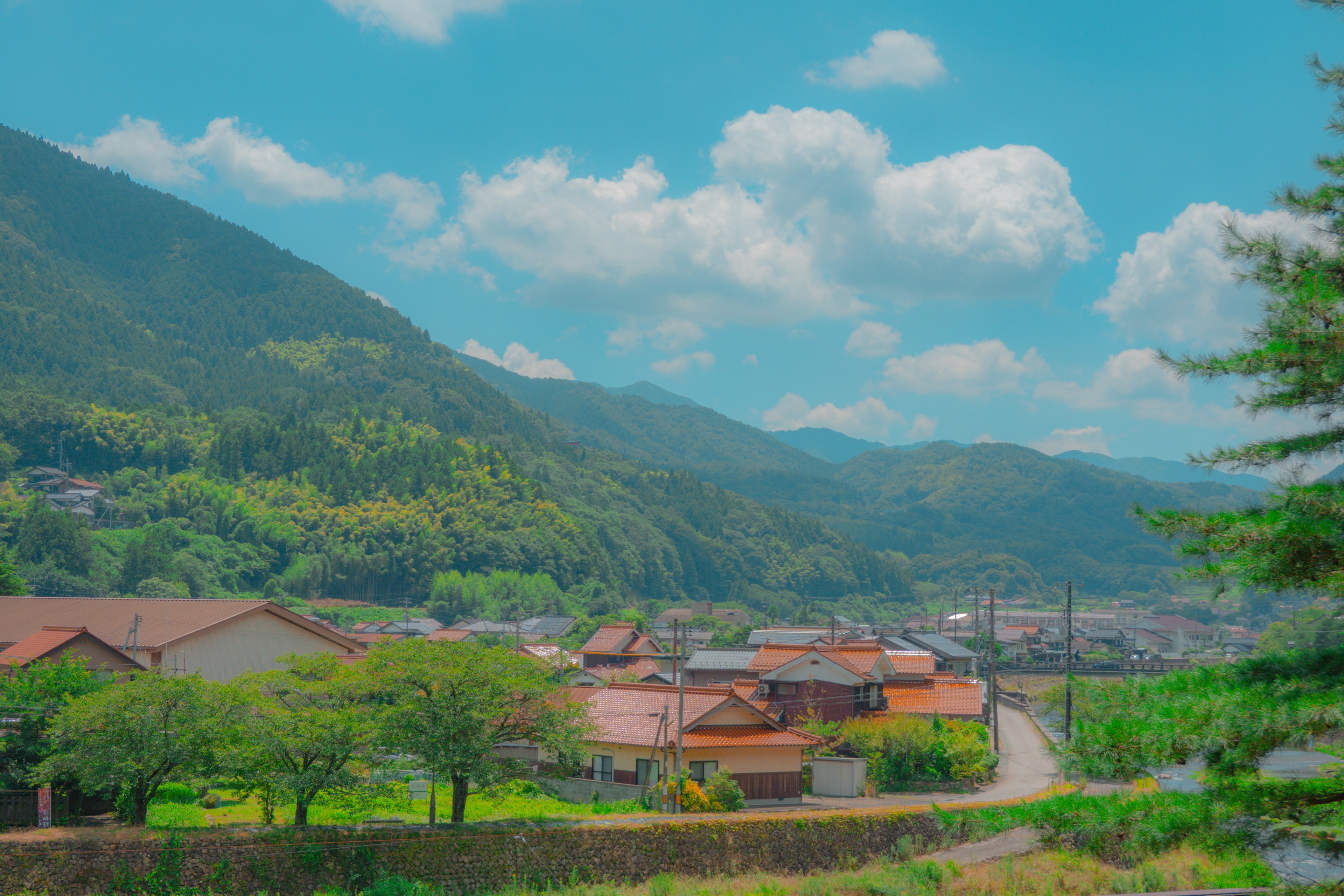 Una vista escénica de un paisaje rural japonés con montañas y casas tradicionales bajo un cielo azul