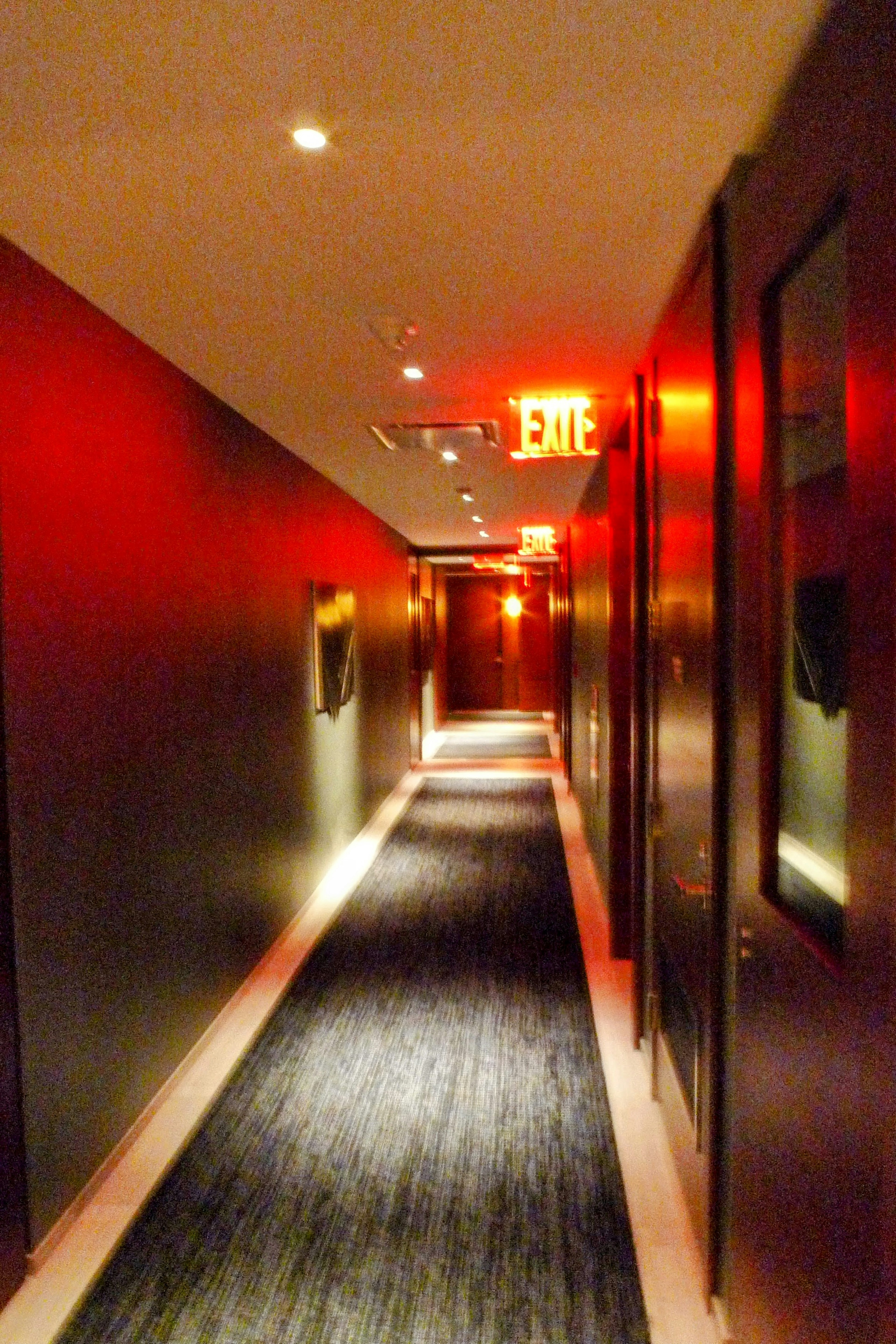 Hotel hallway with striking red lighting dark colored walls and modern design elements