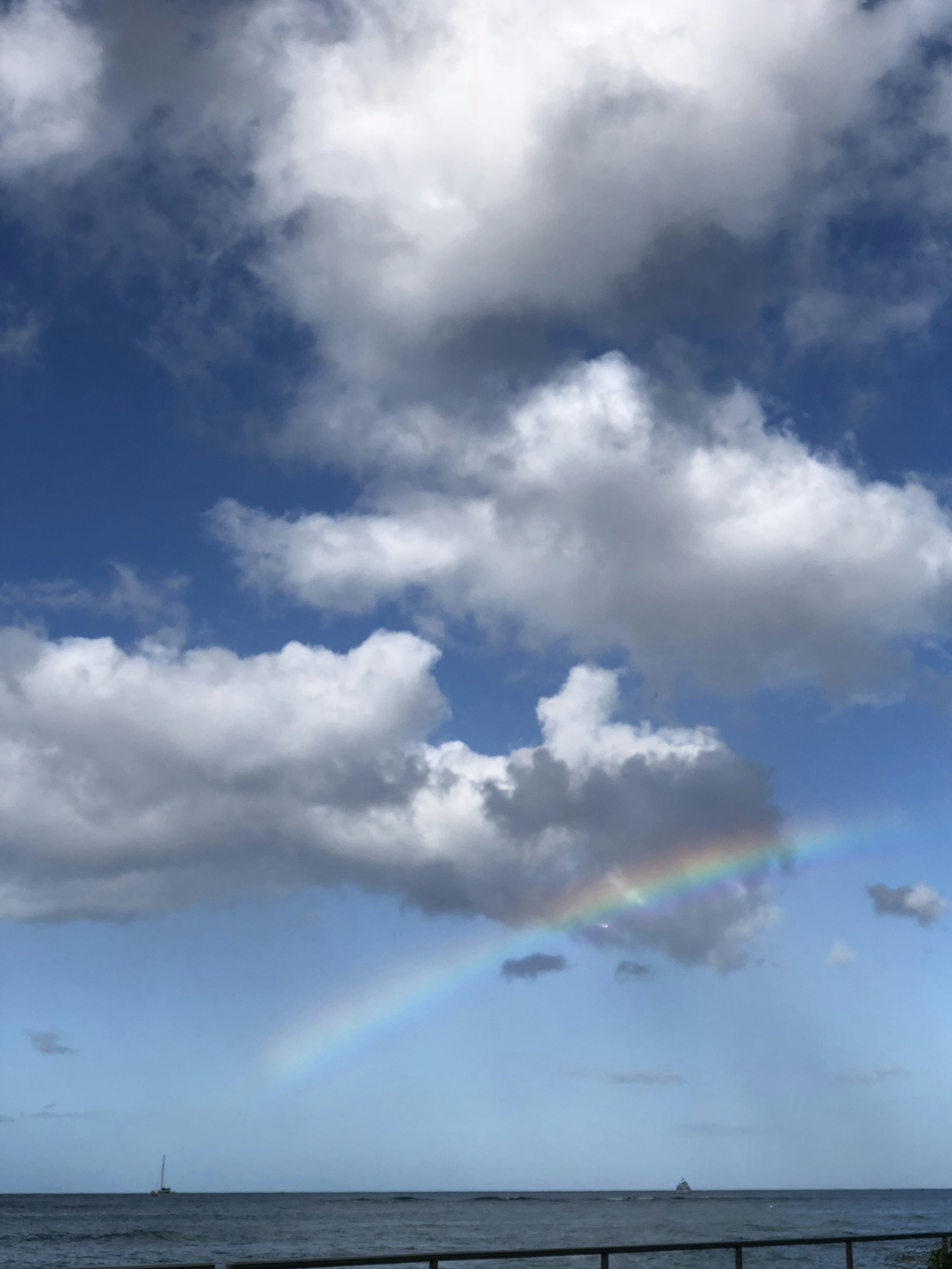 青空の下に虹がかかり雲が浮かぶ美しい風景