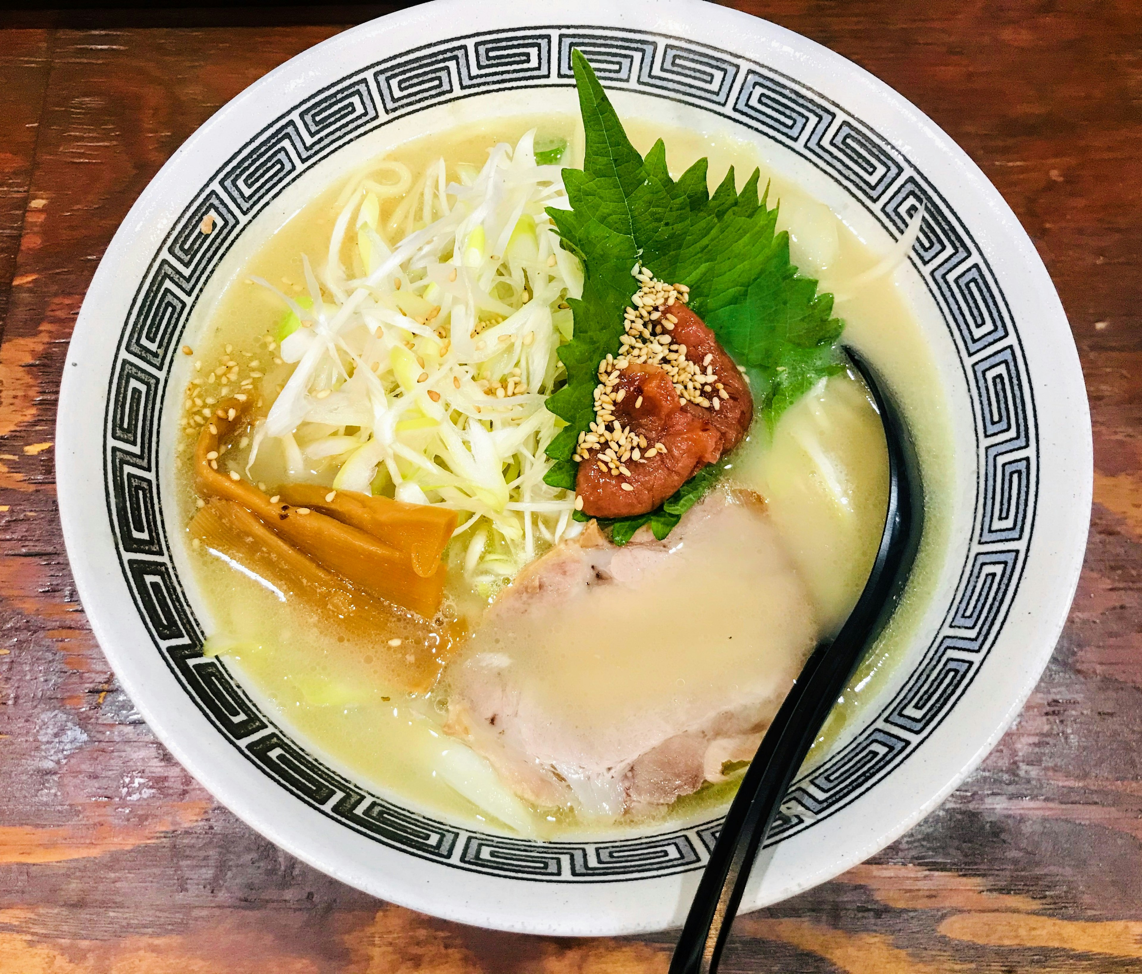 Bowl of ramen topped with sliced chashu, cabbage, shiso, umeboshi, and menma