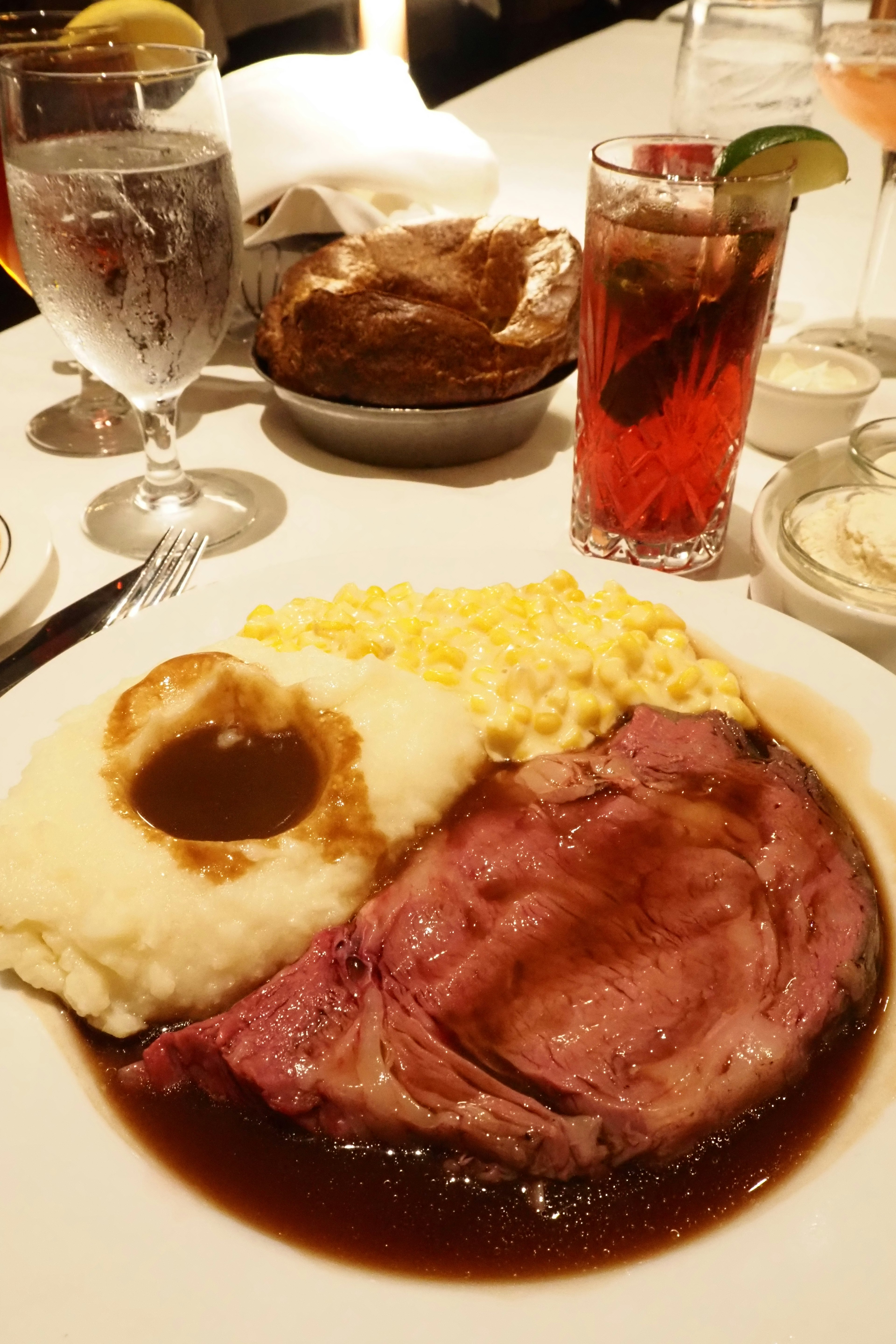 맛있는 로스트 비프 접시와 으깬 감자 소스 옥수수 음료가 보인다