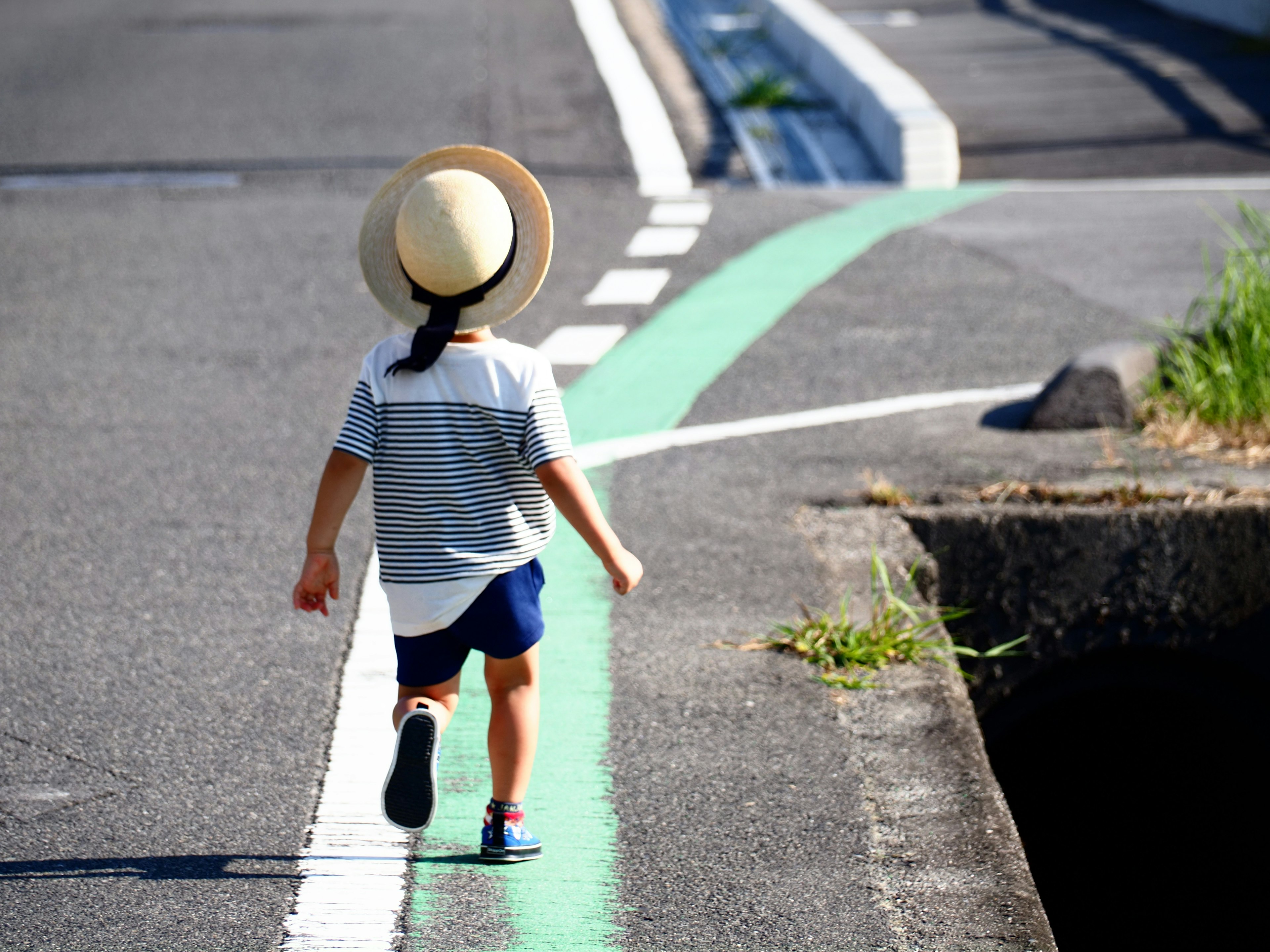 帽子をかぶった子供が道路を歩いている