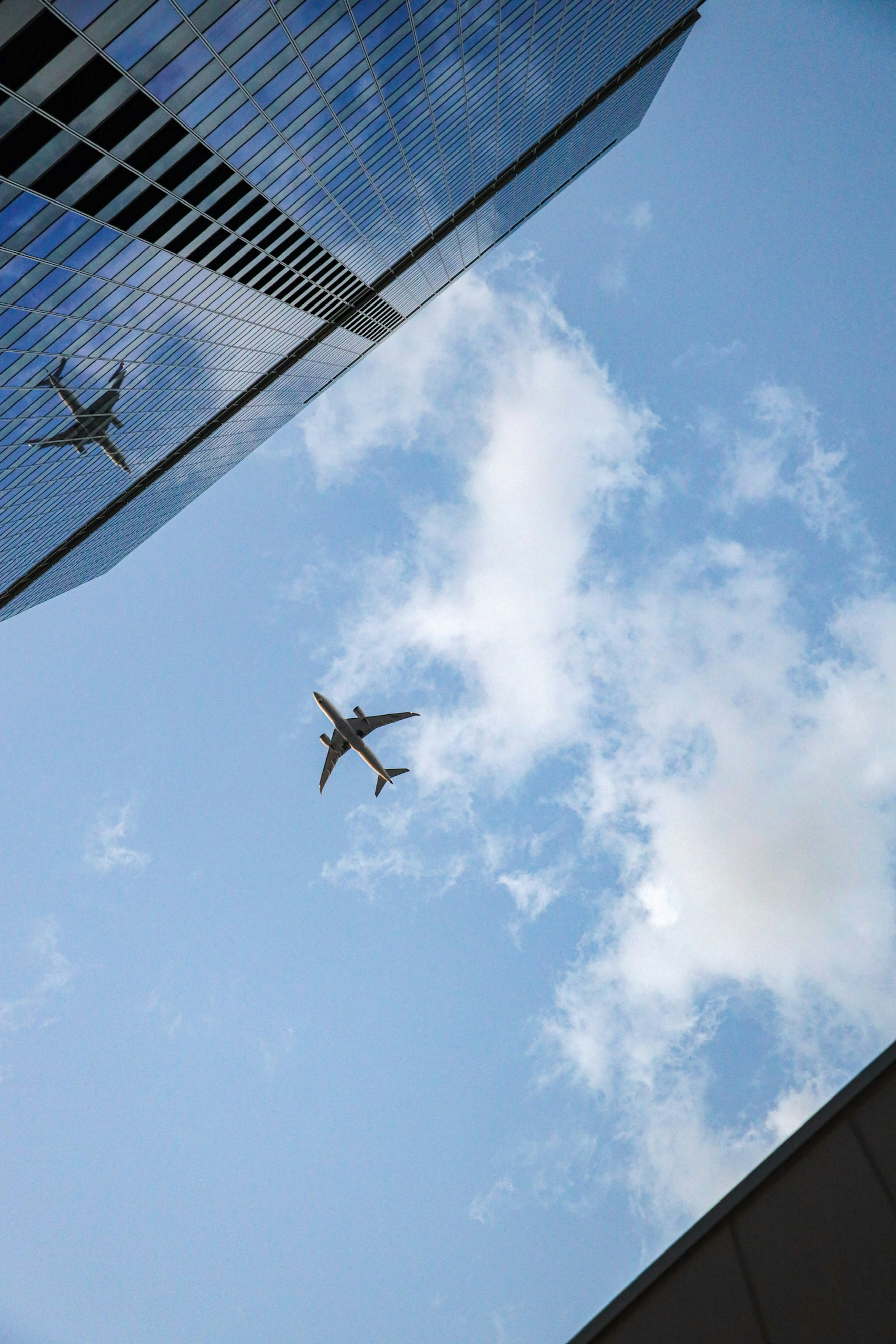 Pemandangan mengesankan pesawat terbang di atas gedung pencakar langit dan langit biru