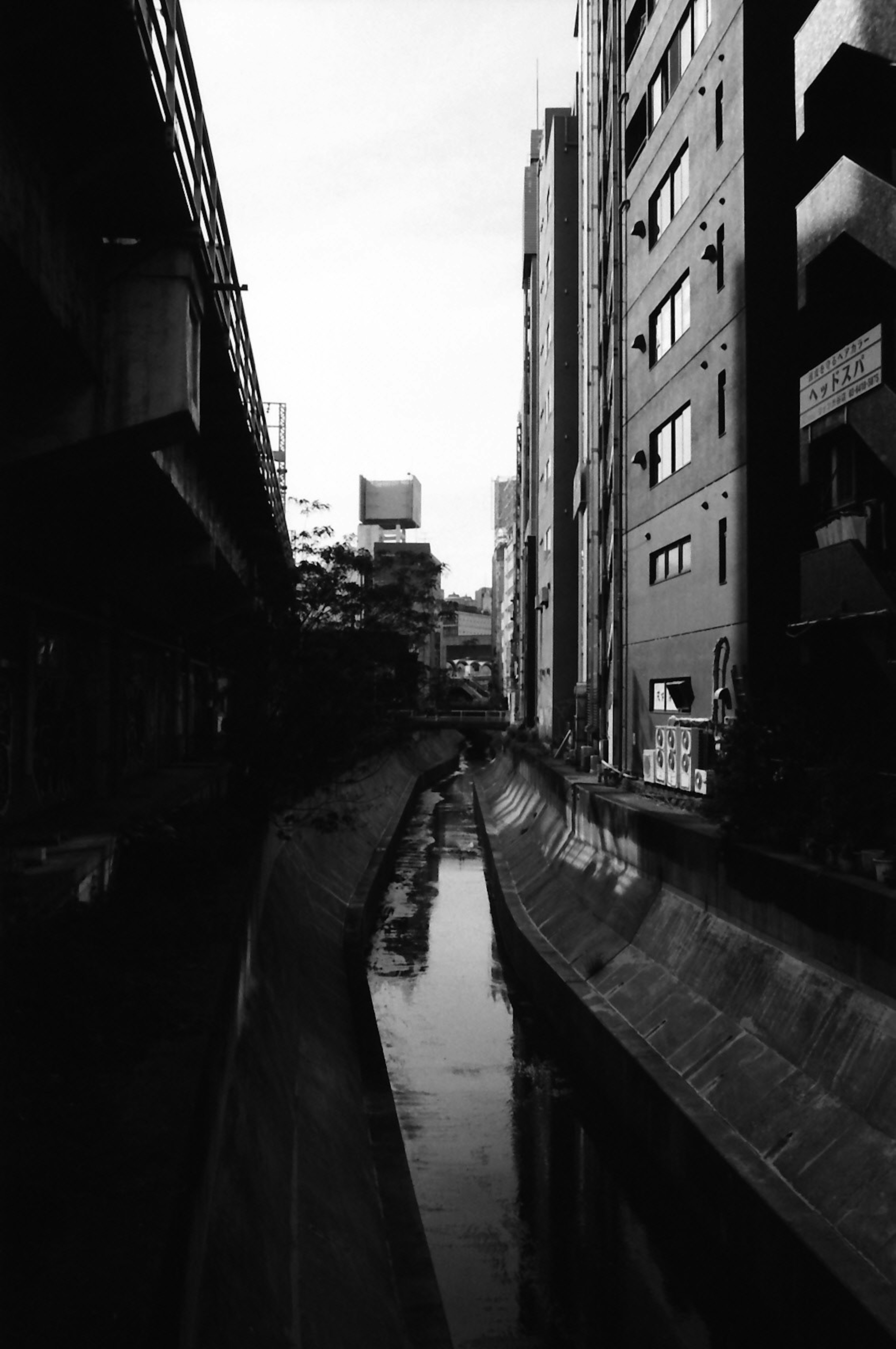 Photo en noir et blanc d'un cours d'eau urbain avec des immeubles