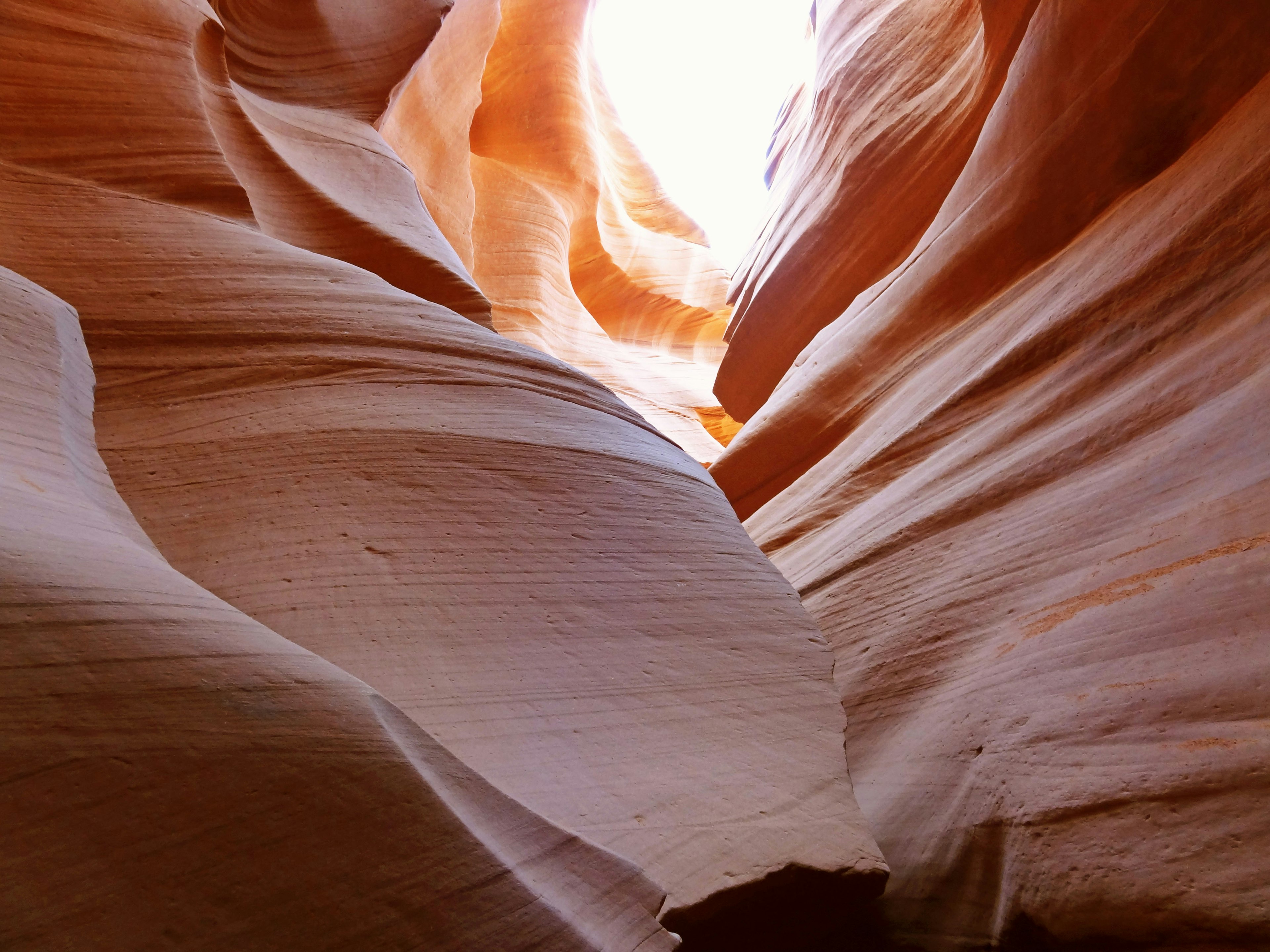 Antelope Canyon with smooth red rock layers and a light opening