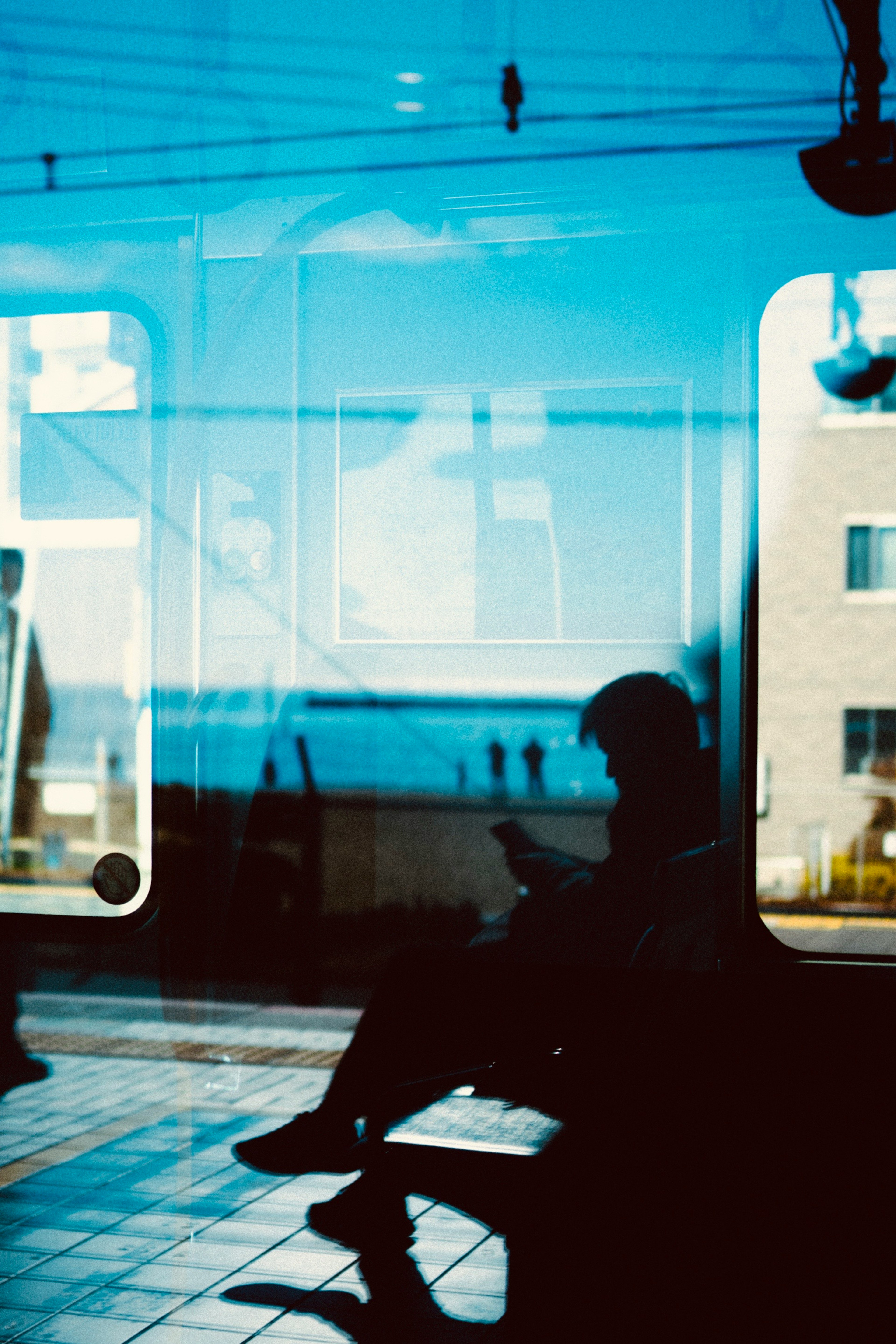 Silueta de una persona sentada frente a una ventana reflectante azul