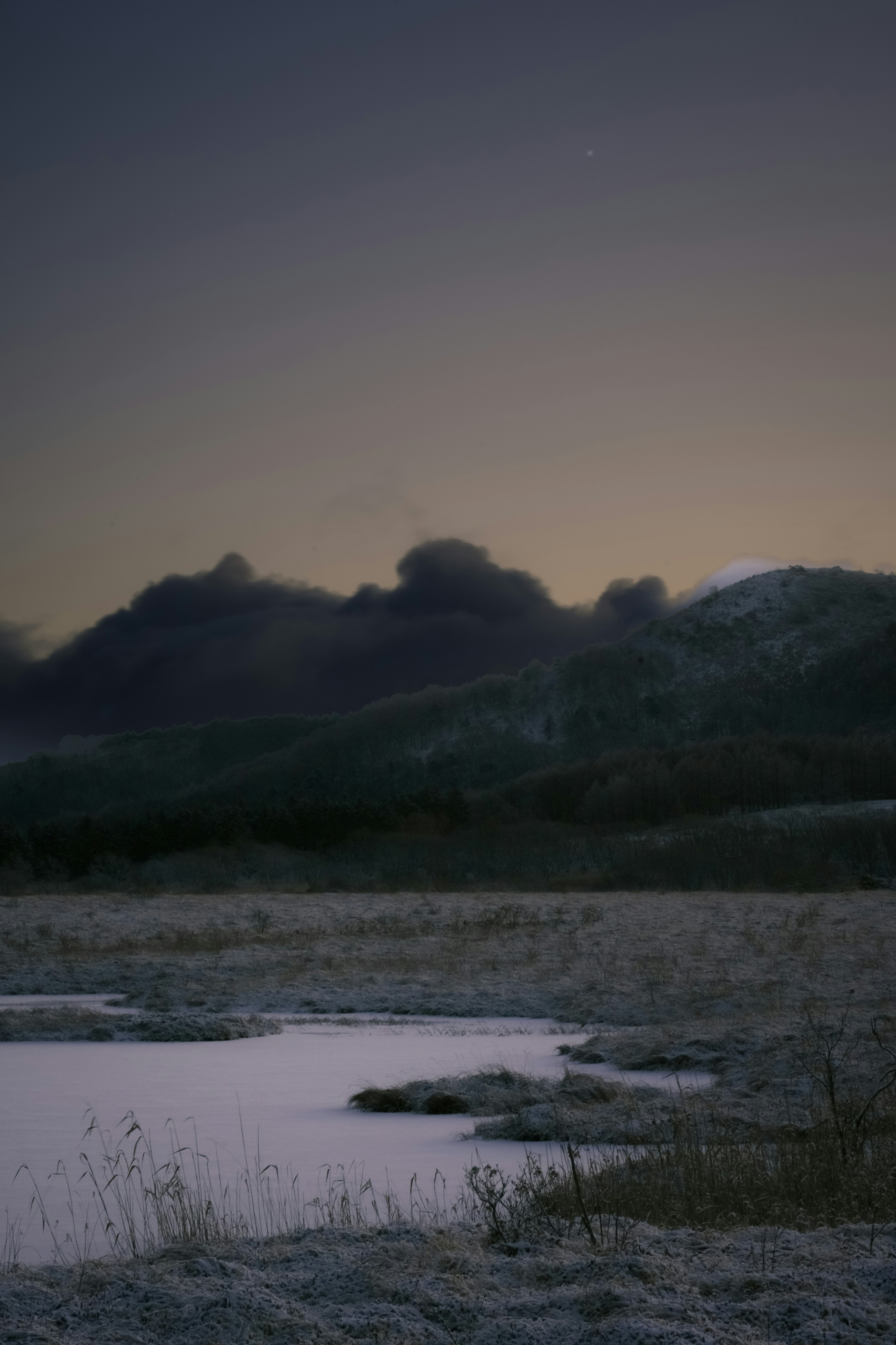 雪のある風景と山々のシルエットが見える夕暮れの情景