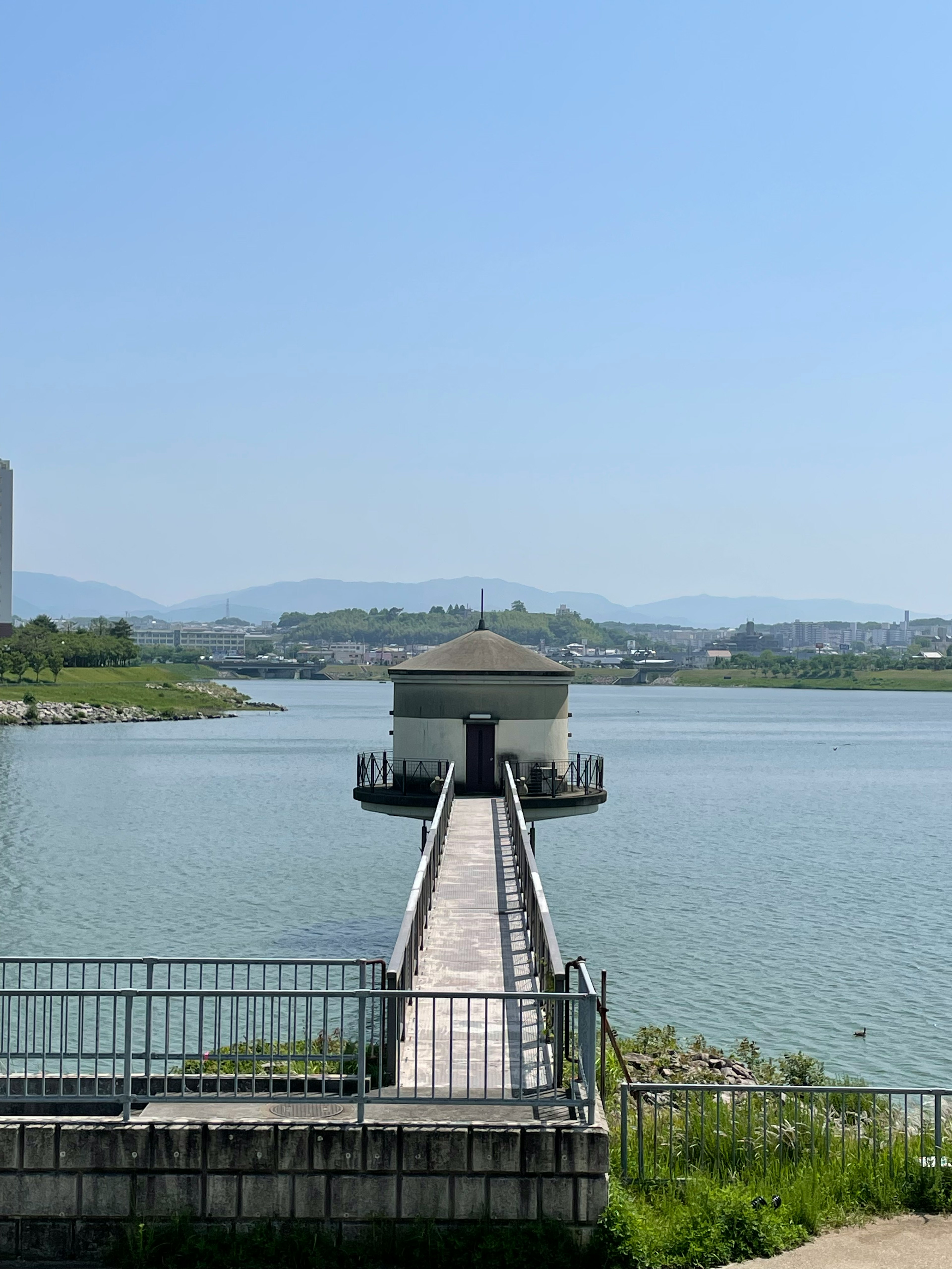 青空の下にある水の上の小さな建物と長い桟橋