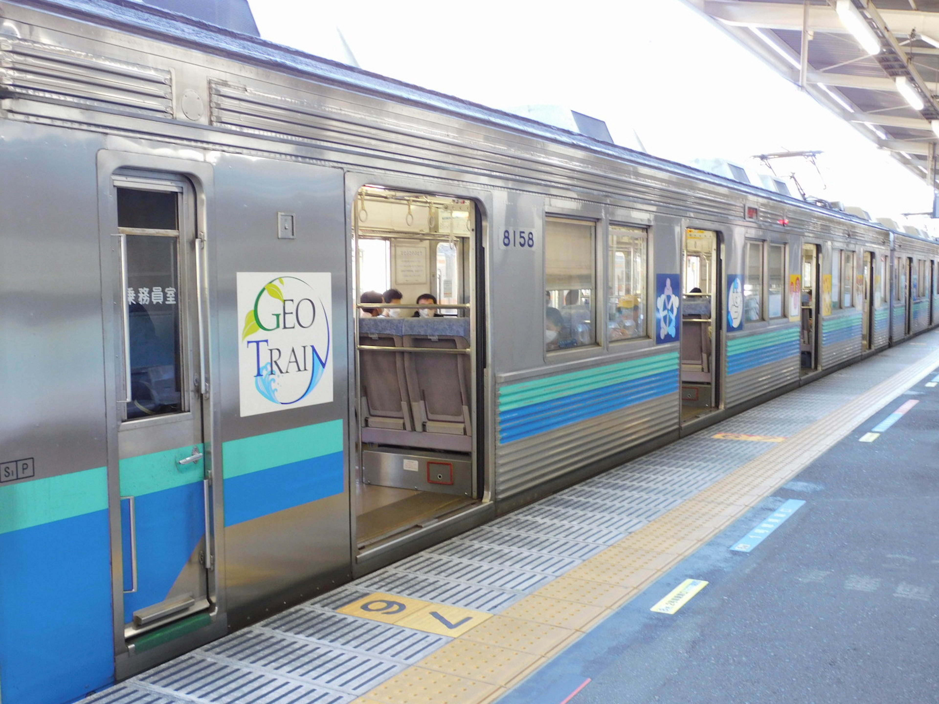 Open train doors on a platform with blue and silver train cars