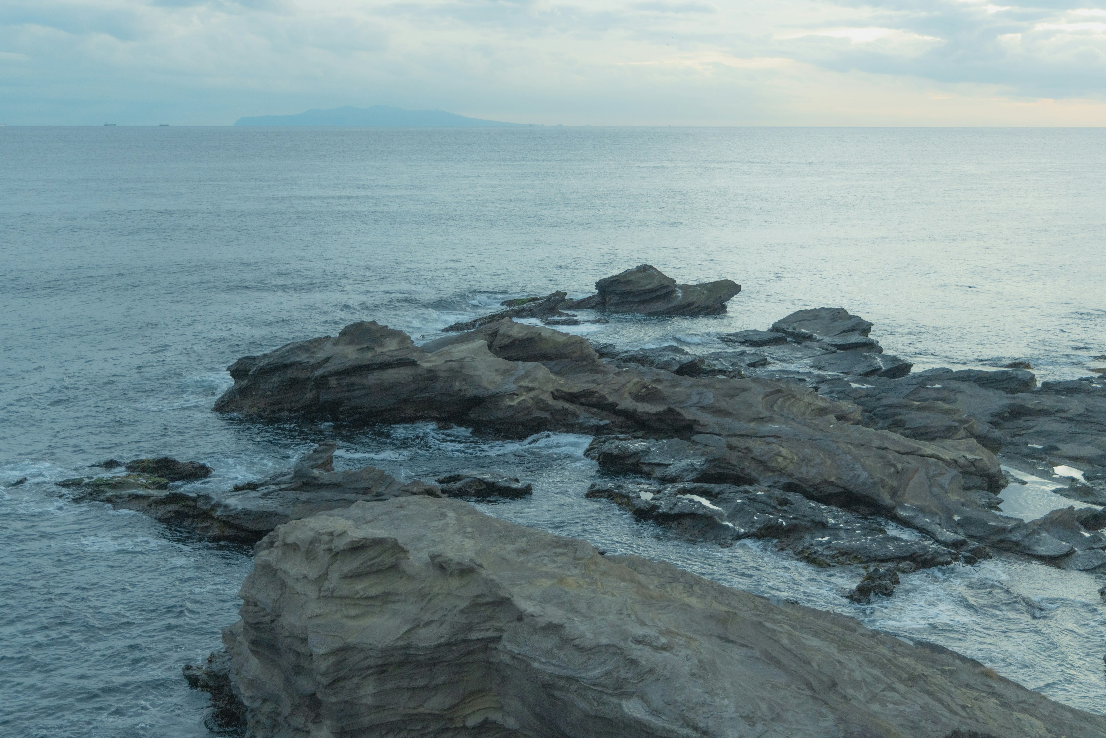 Coastal landscape with rocks calm water and overcast sky