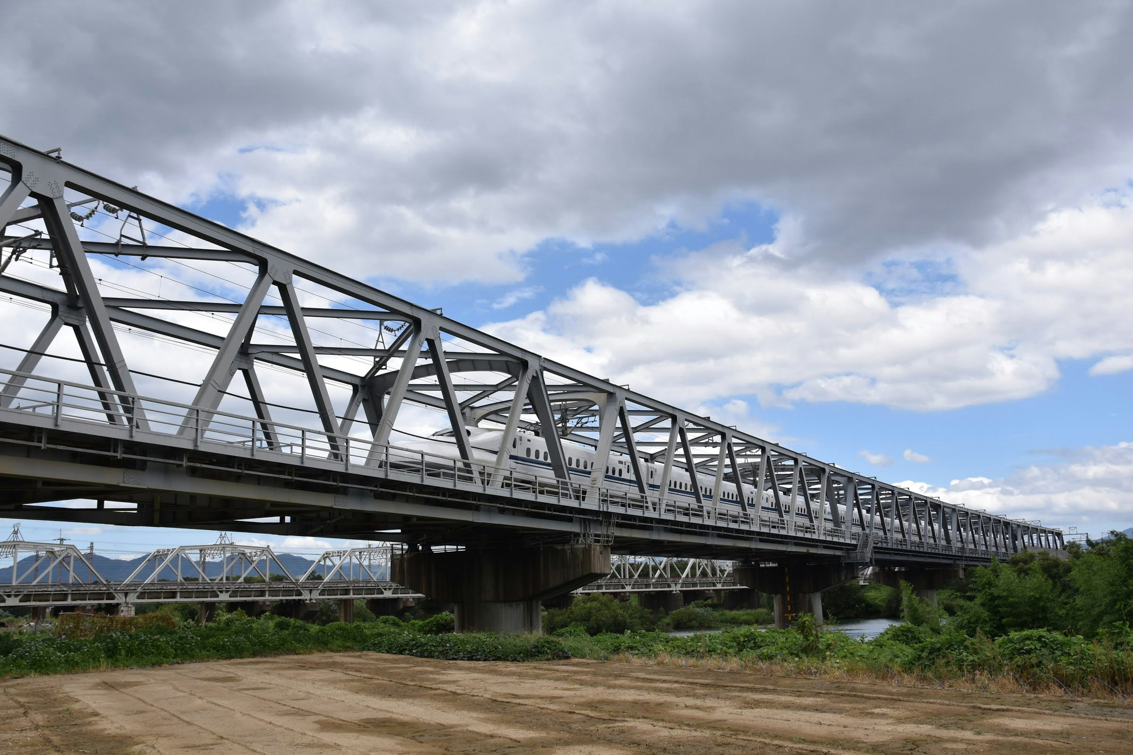 สะพานเหล็กสีเงินทอดยาวใต้ท้องฟ้าที่มีเมฆ