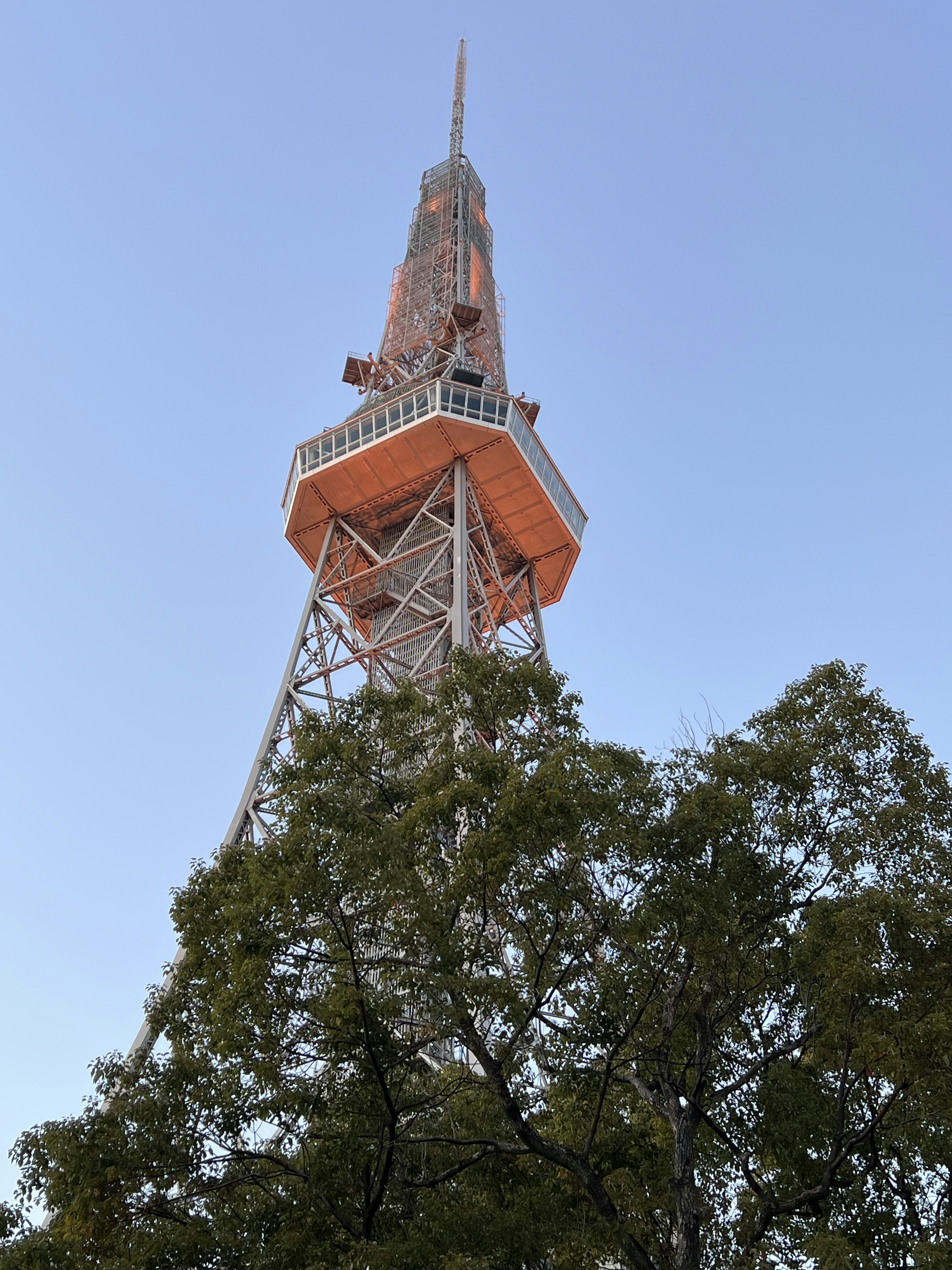 Nagoya Fernsehturm von unten mit grünen Bäumen im Vordergrund