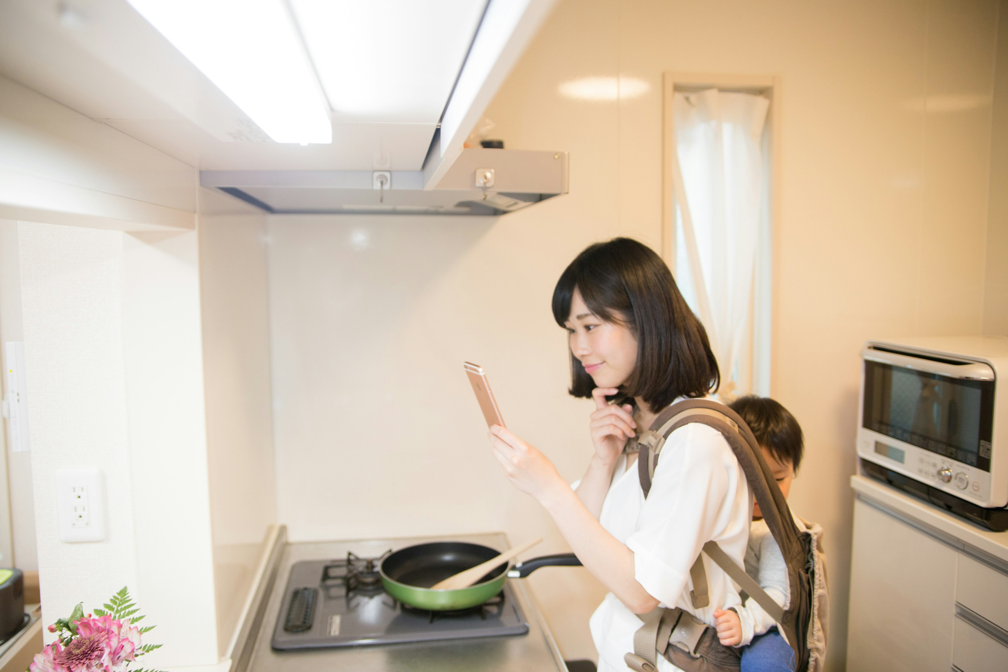 Donna che guarda lo smartphone mentre cucina in cucina