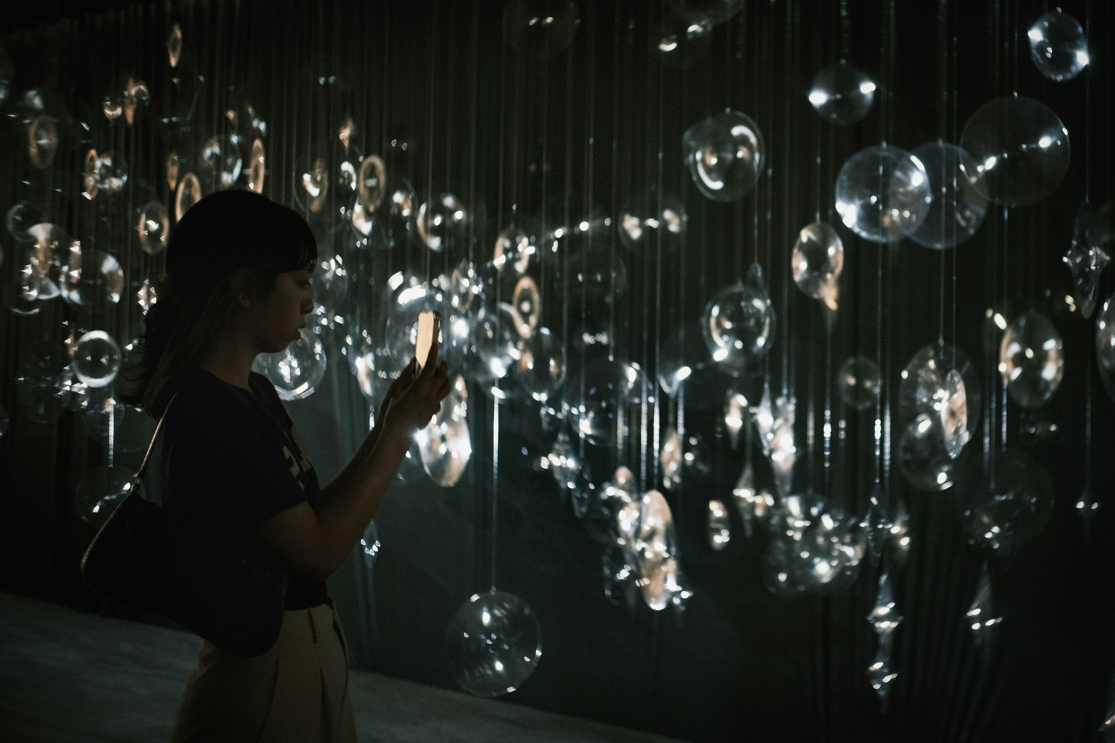 Une femme regardant des sphères transparentes lumineuses dans un espace faiblement éclairé