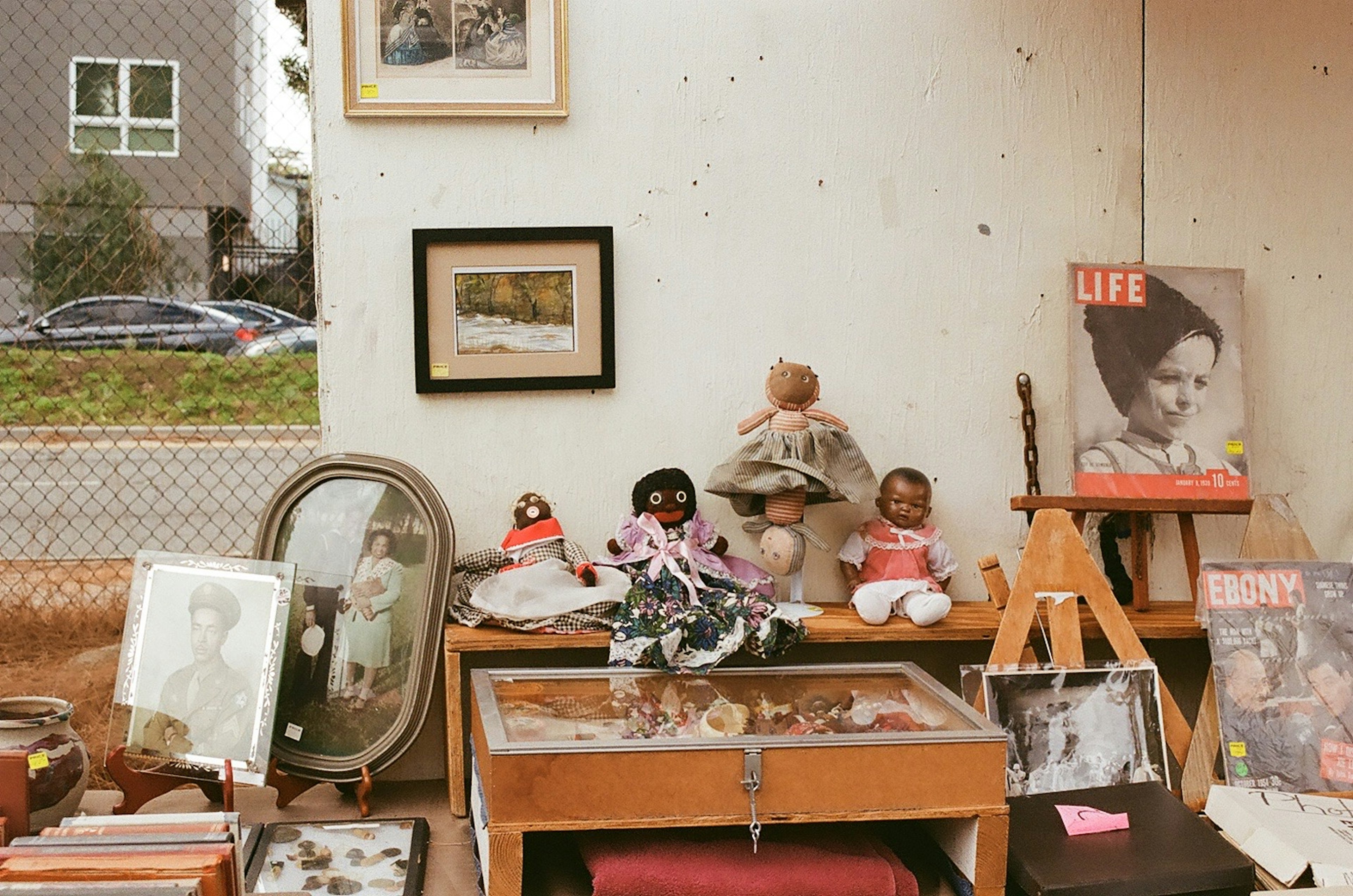 Interior of an antique shop featuring vintage dolls and framed photographs