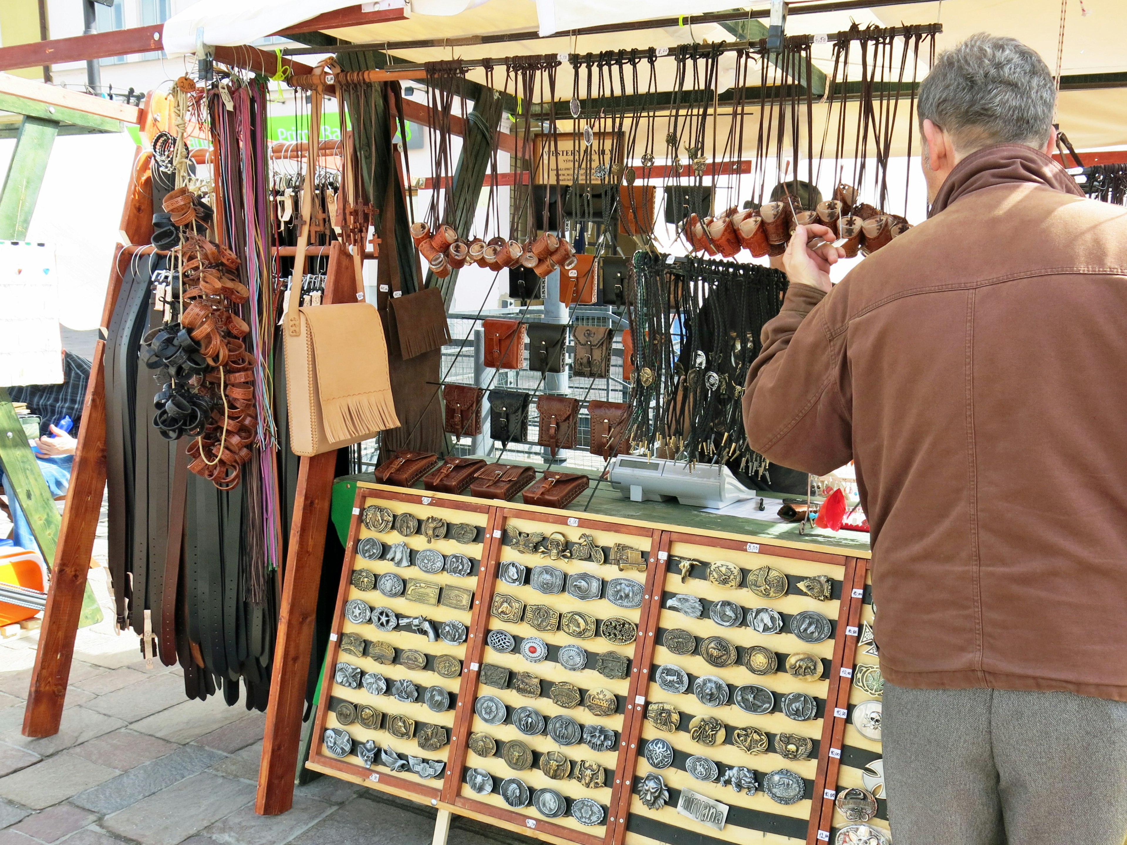 Market stall displaying leather goods with a customer