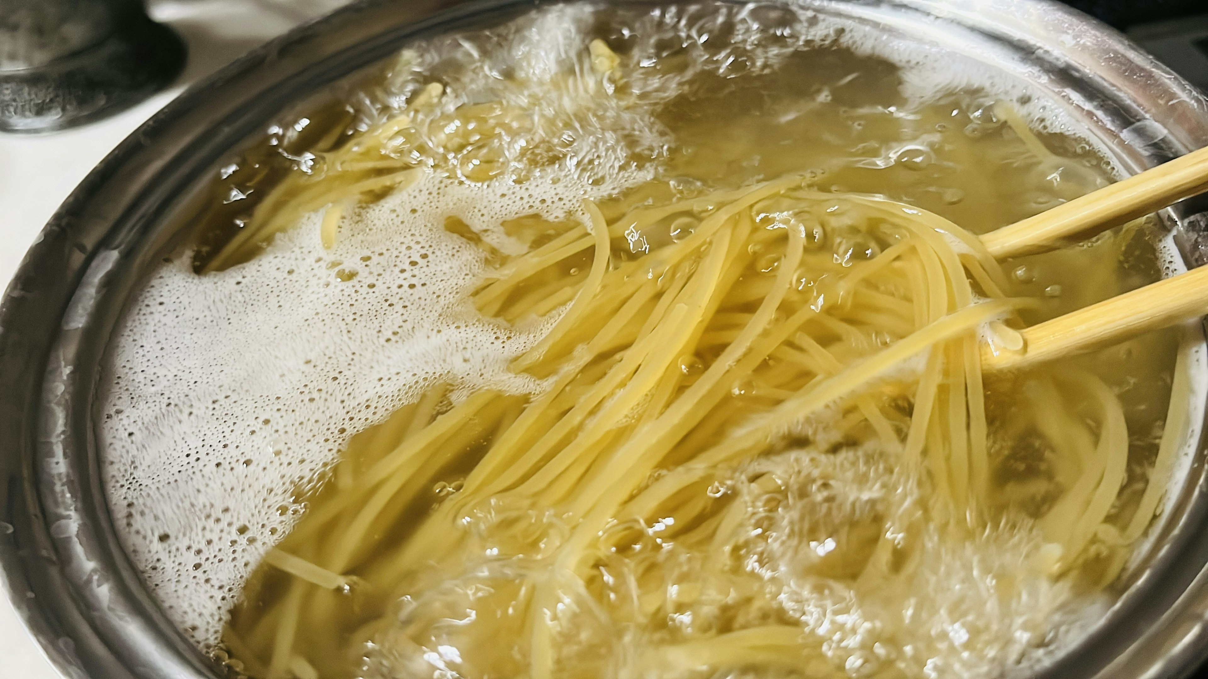 Spaghetti kochen in einem Topf mit Essstäbchen