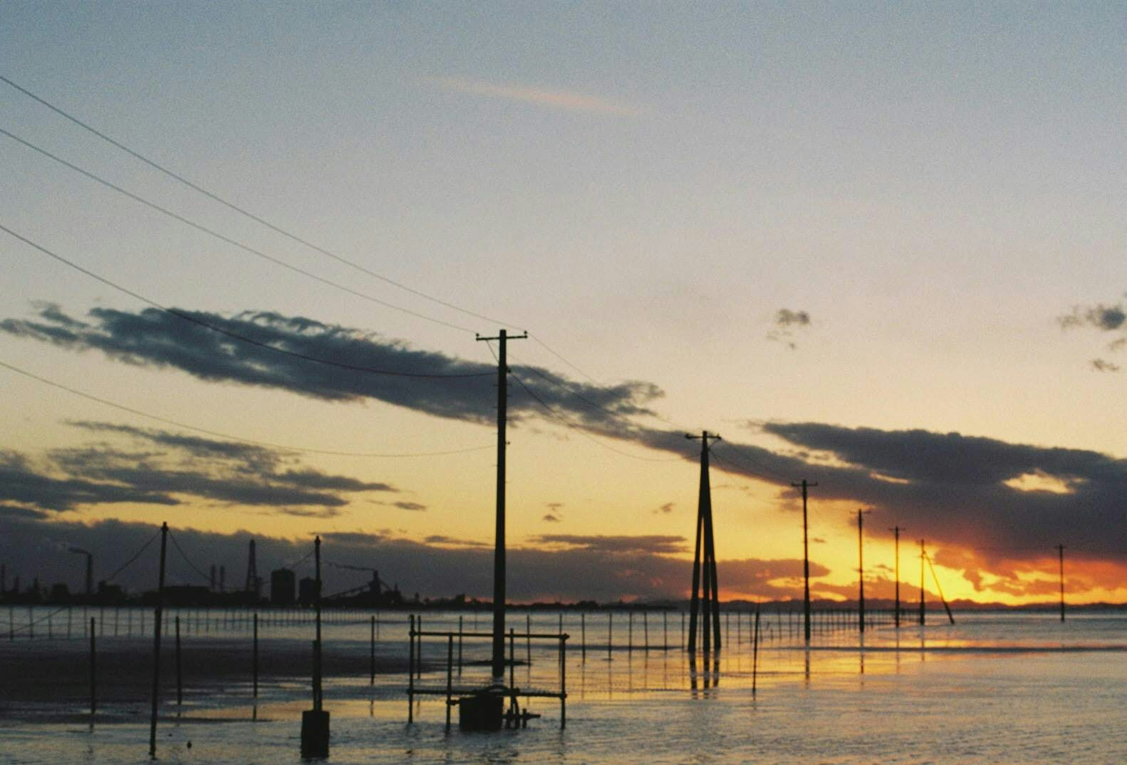 Paesaggio con pali elettrici in silhouette contro un cielo al tramonto