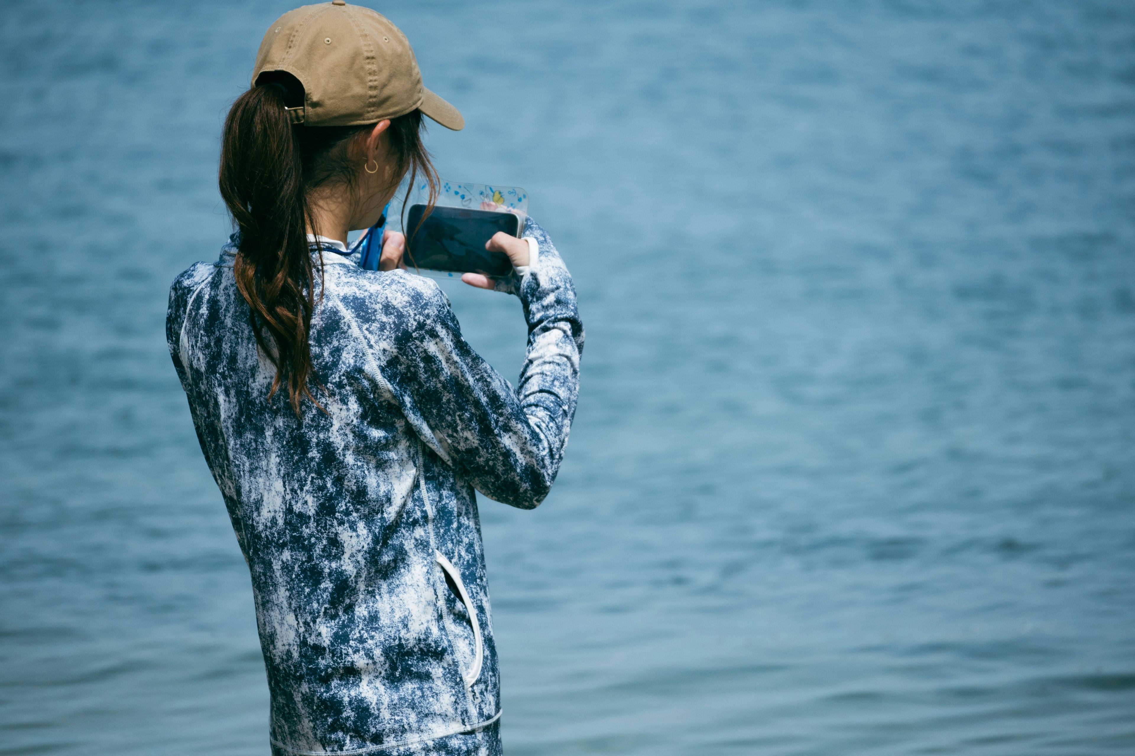 Frau hält Smartphone am Meer