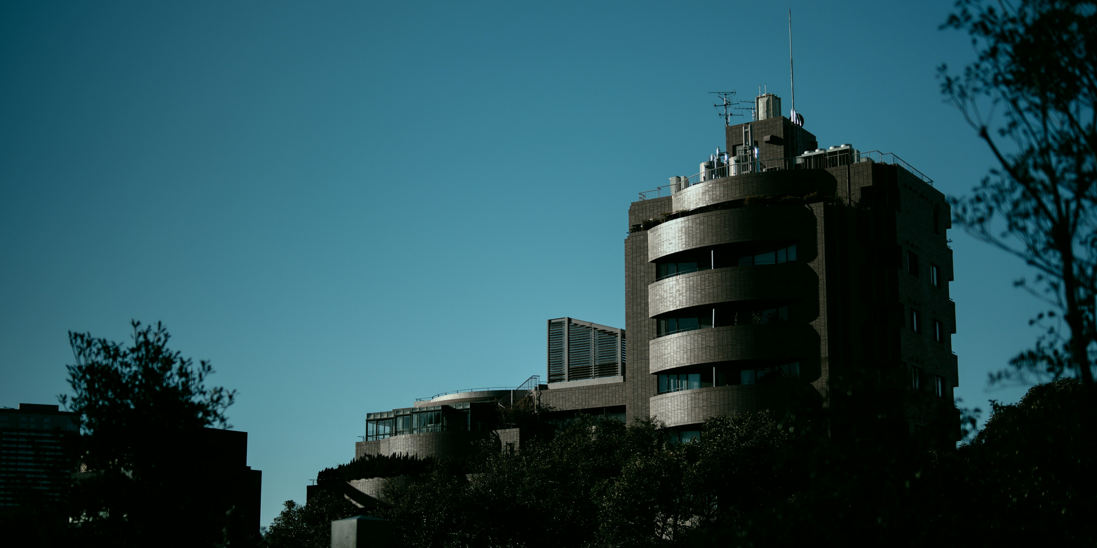 Modernes Gebäude unter blauem Himmel mit geschwungenem Design und metallischer Fassade